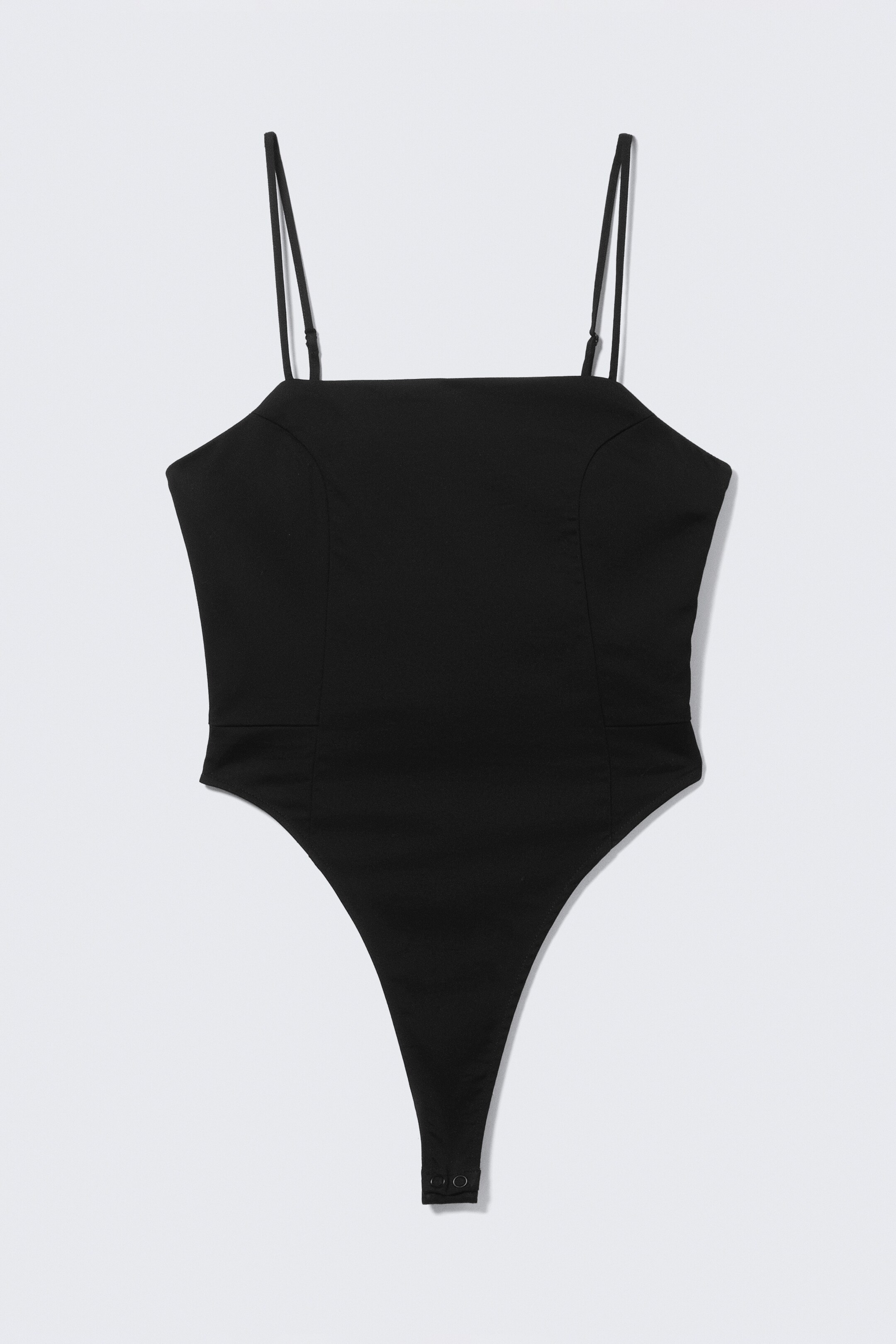 Agrandir l'image: Un body noir présente son DEVANT, présentant un corps ajusté confectionné en sergé structuré. Il affiche un décolleté carré, des bretelles fines ajustables, et une jambe haute avec une fermeture à boutons-pression à la base.
