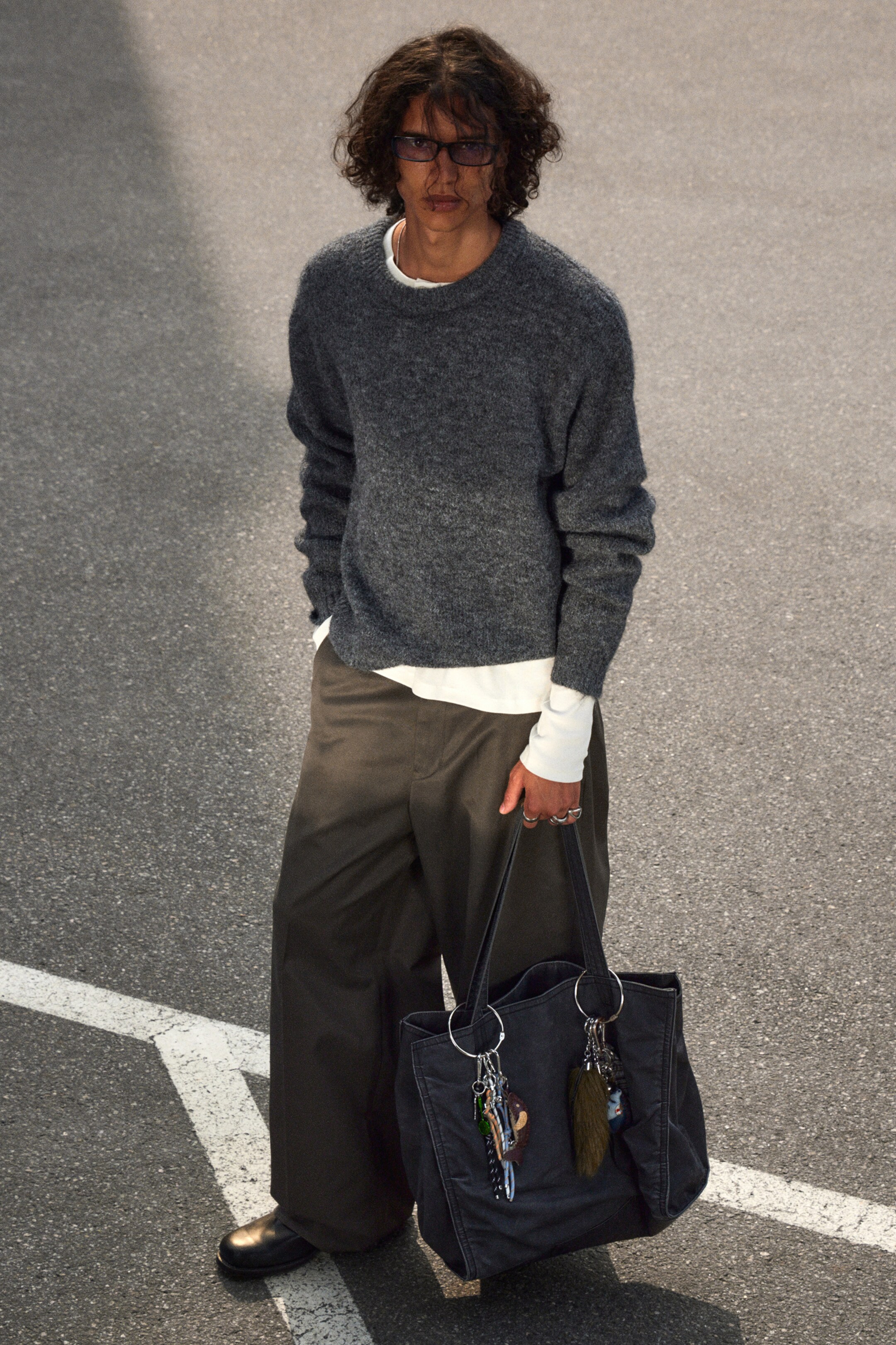 Agrandir l'image: Un sac fourre-tout en tissu gris foncé est tenu, mettant en valeur deux poignées supérieures et deux grands anneaux en O de couleur argent attachés à son bord supérieur. Plusieurs porte-clés pendent de ces anneaux.