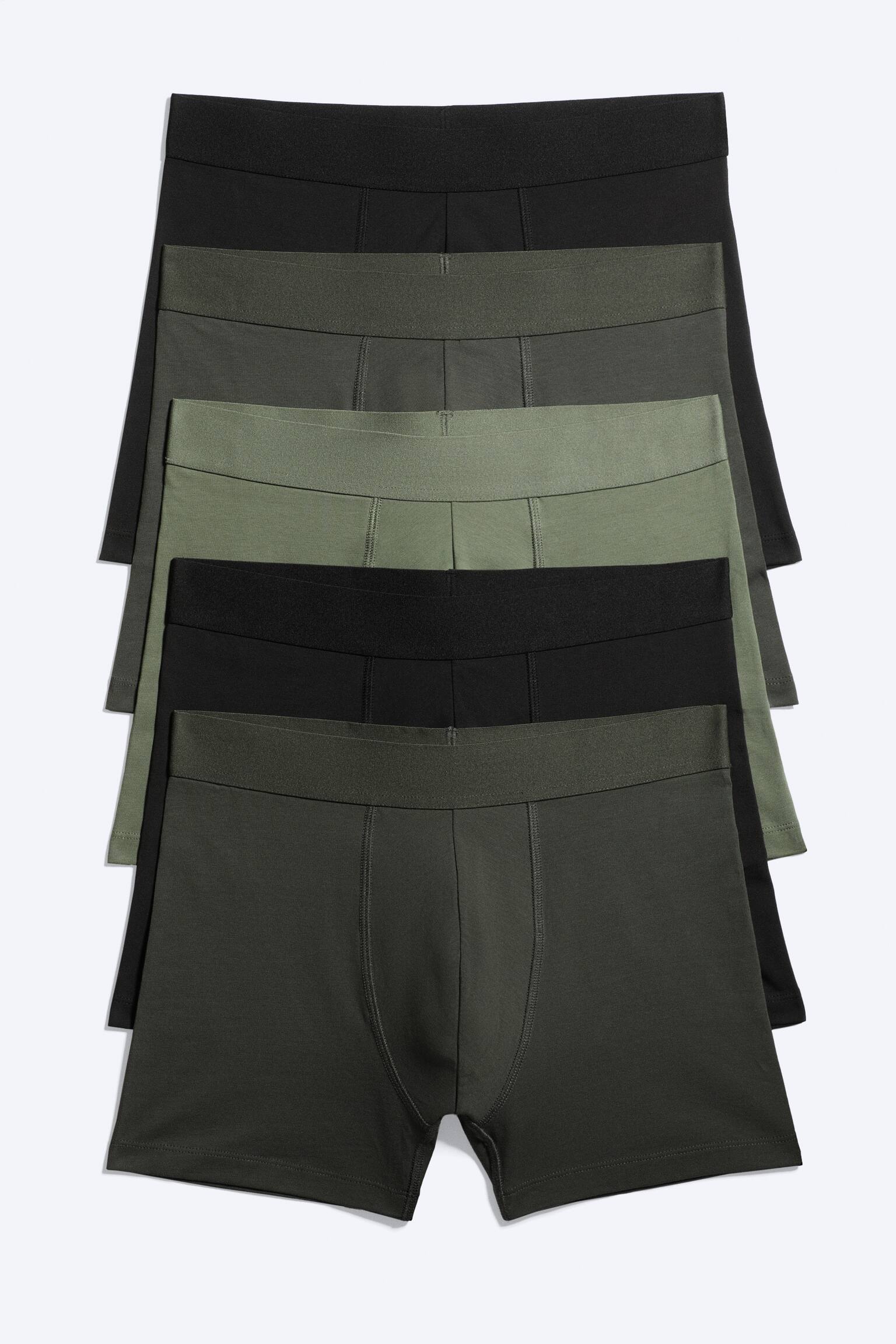 Fem par boxershorts är prydligt staplade i växlande svarta och olivgröna färger, där varje par har en elastisk midja och en konturerad frontpanel.