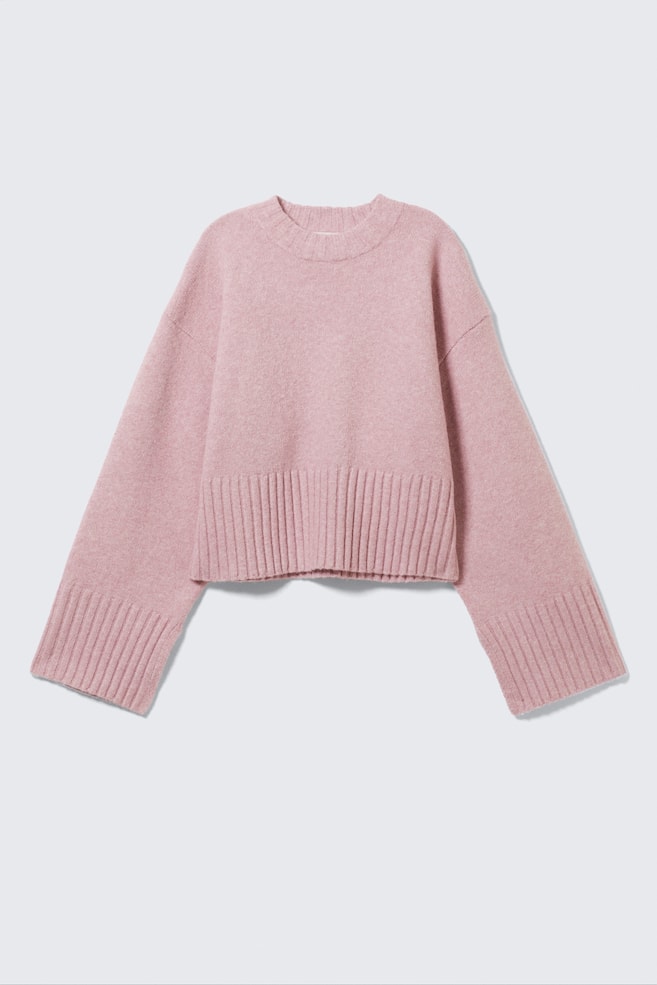Różowy sweter prezentuje swój przedni widok, charakteryzując się puszystą dzianinową fakturą. Jest zaprojektowany z okrągłym dekoltem, szerokimi długimi rękawami zakończonymi ściągaczami oraz ściągaczowym dołem, który wydaje się być skrócony. - 1