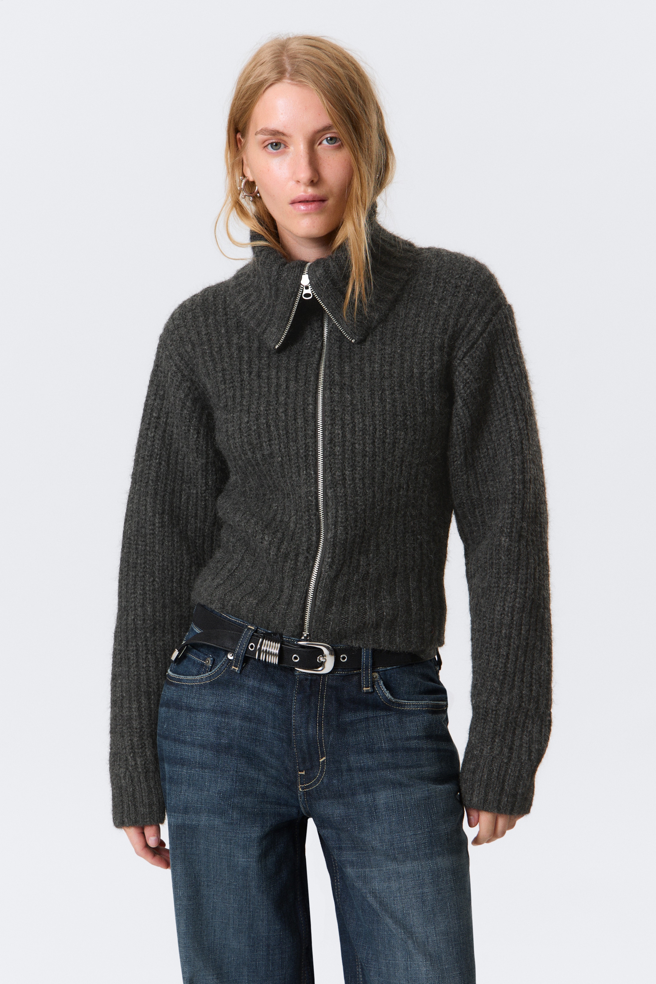 Agrandir l'image: Un cardigan en maille gris foncé est présenté de face, avec un tricot côtelé épais, une fermeture éclair complète avec une fermeture éclair de couleur argentée, un col cheminée dézippé et posé à plat, et un ourlet court.