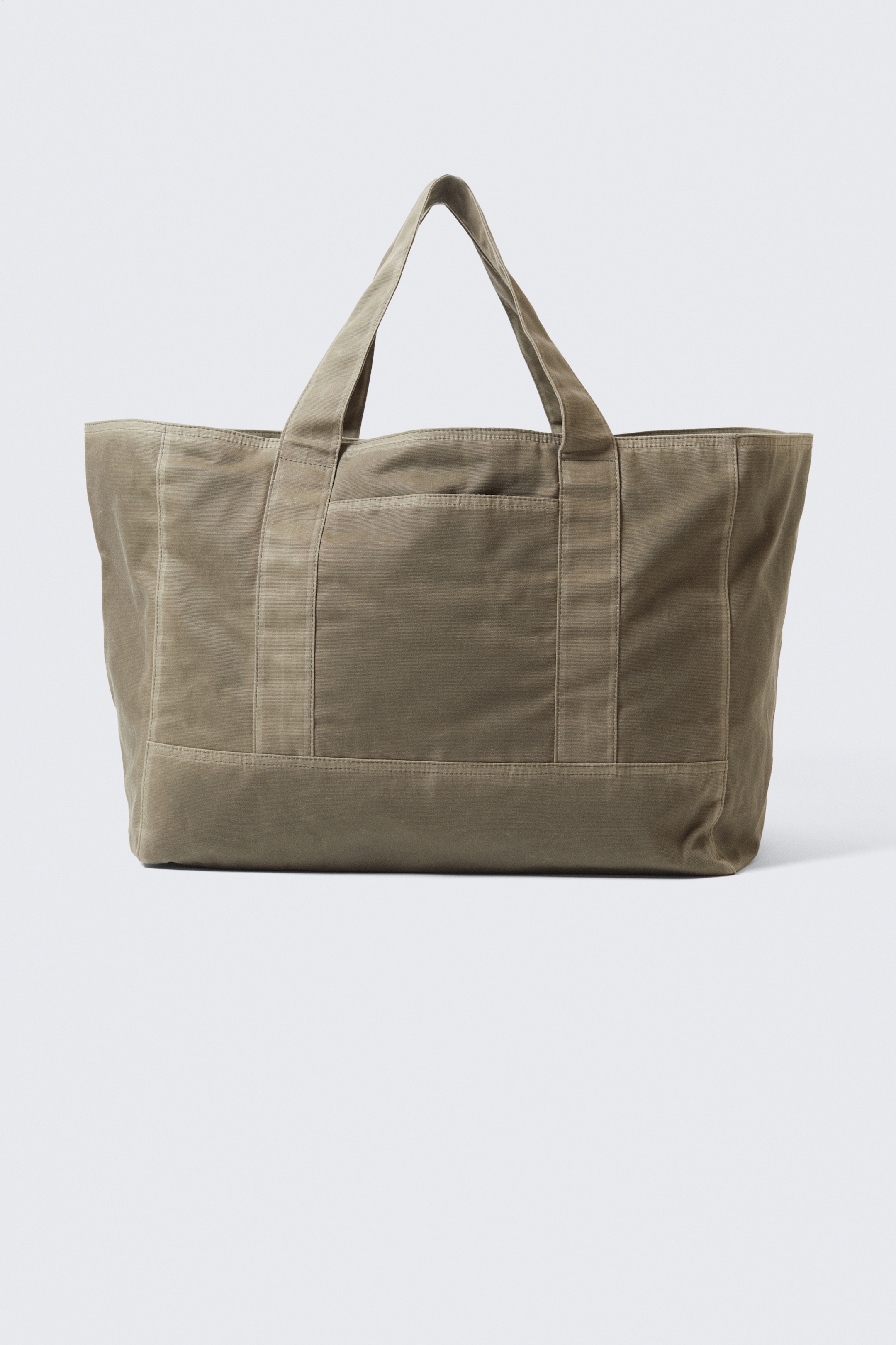 Agrandir l'image: Un sac fourre-tout olive vert, orienté vers l'avant, est debout, affichant une forme structurée et une finition robuste. Il est doté de poignées jumelles renforcées, de coutures apparentes, et d'une poche extérieure surdimensionnée sur son devant.