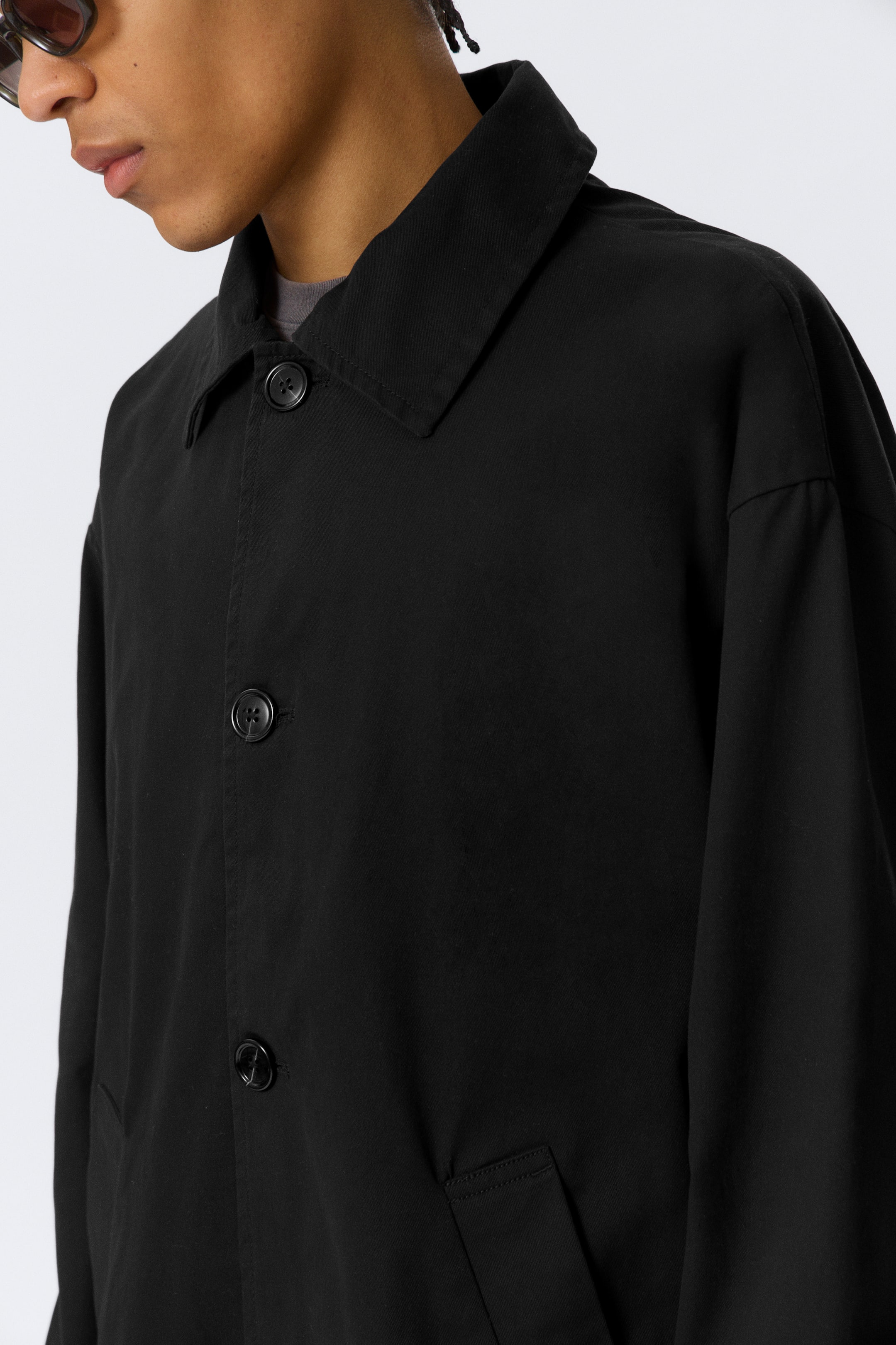 Agrandir l'image: Une veste noire à boutons sur le devant, dotée d'un col classique, de boutons noirs visibles sur le devant et de poches passepoilées. Elle est portée sur un t-shirt gris.