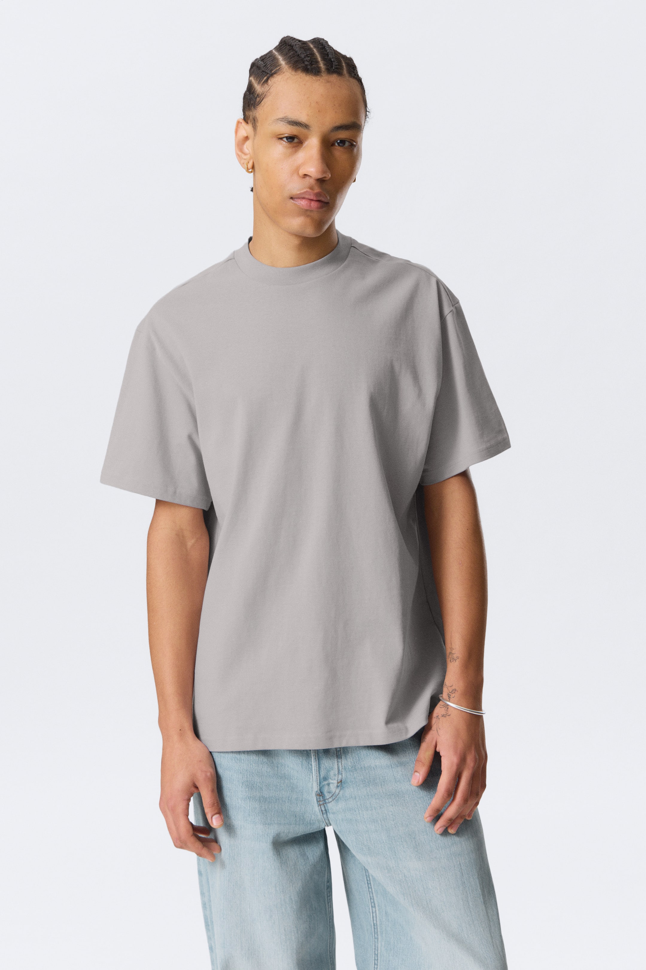 Agrandir l'image: Un t-shirt gris est présenté en vue de face, avec un col montant et des manches courtes, offrant une coupe décontractée.