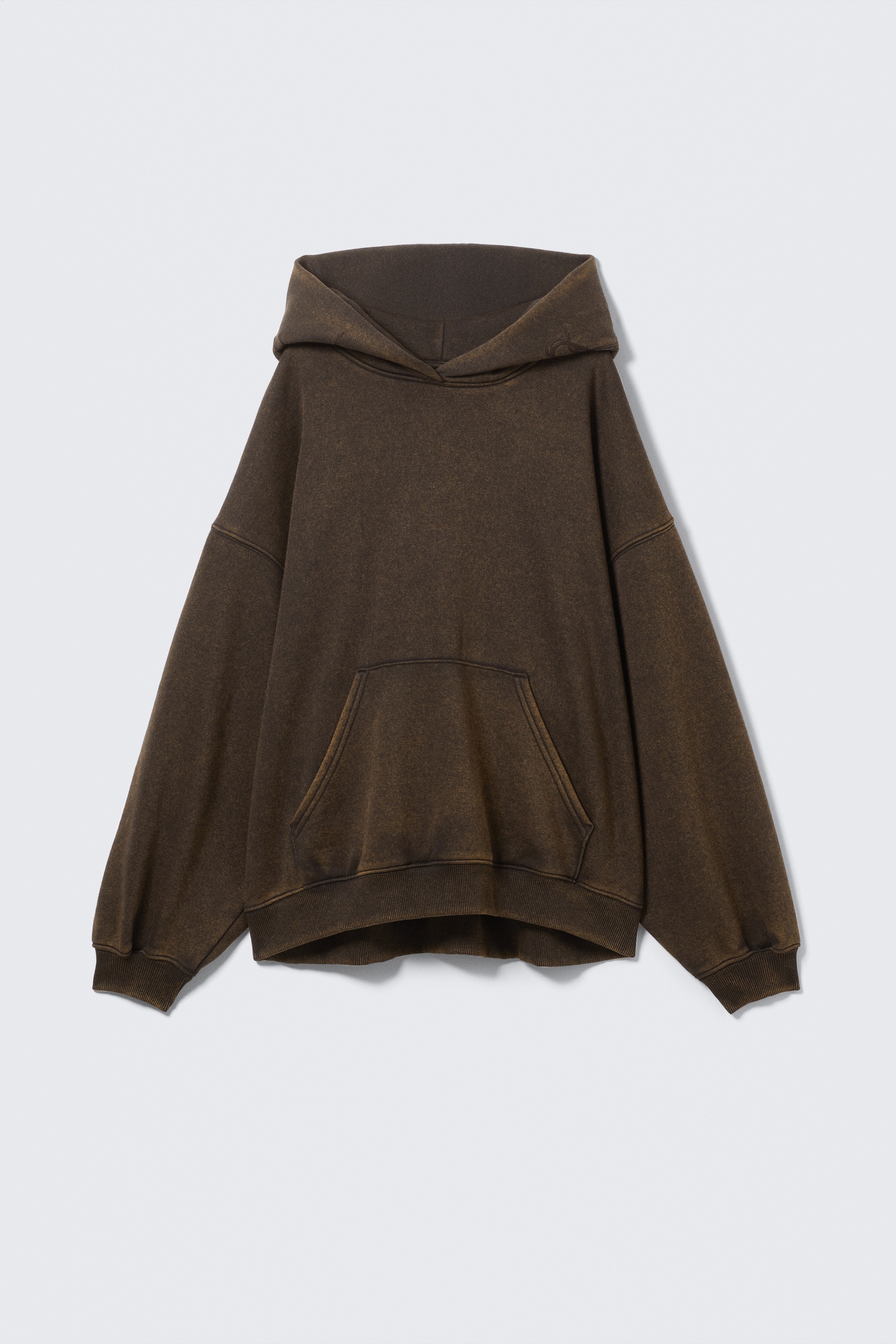 Visa större bild: En överdimensionerad, mörkbrun hoodie presenteras framifrån. Den har en tvättad tygstruktur, nedfallna axlar, en stor känguruficka och ribbade muddar och fåll.