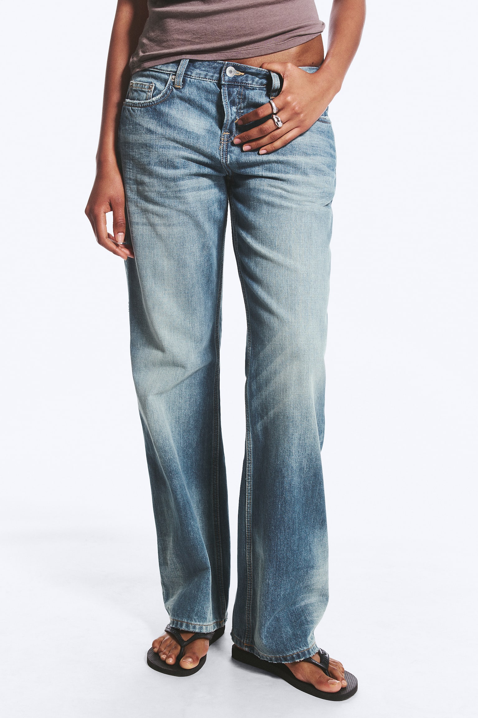 Die blauen Denim-Jeans werden von vorne gezeigt und verfügen über eine verwaschene Optik mit Whiskering an Oberschenkeln und Knien. Sie sind mit einem Bund, Gürtelschlaufen, Fronttaschen inklusive Münztasche sowie einem Knopf- und Reissverschluss ausgestattet und präsentieren einen geraden Beinverlauf. - 1