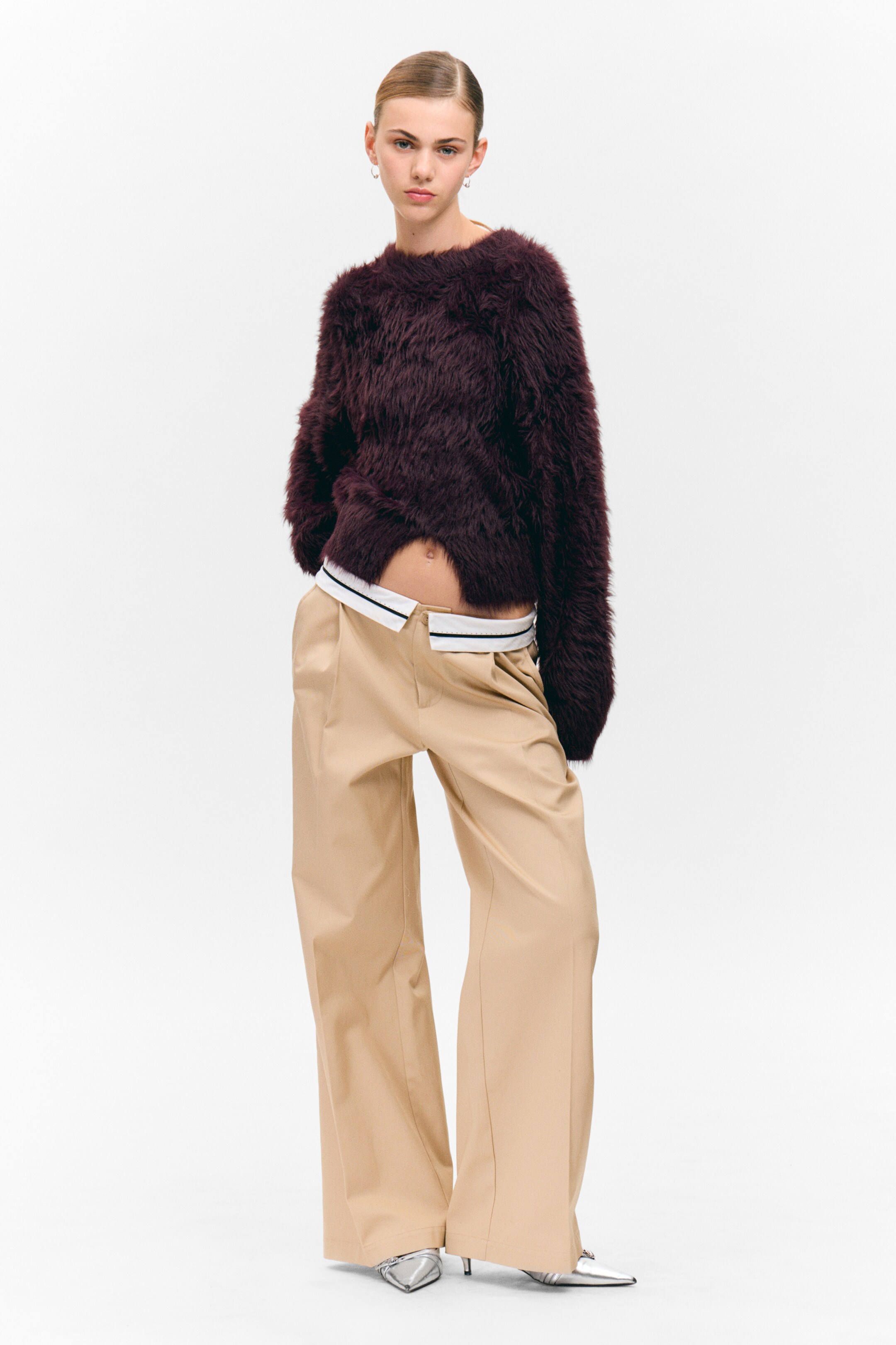 Se større billede: En bordeaux strikket sweater præsenteres fra FRONTEN, med en kort silhuet og en fluffy tekstur. Den er designet med en rund halsudskæring, lange ærmer og en center slids i den nederste kant, der afslører bærerens mave.