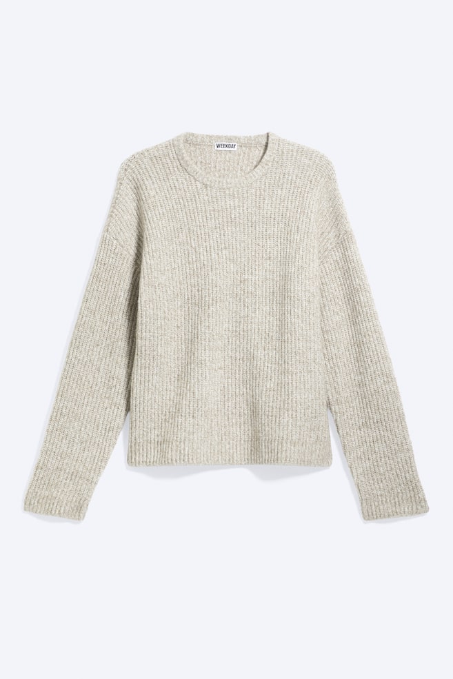 Un pull coupe décontractée, en beige clair chiné, est présenté de face, mettant en avant une construction en maille côtelée texturée sur lâensemble. Le modèle présente un col rond côtelé, des épaules tombantes et des manches longues avec des poignets côtelés décontractés. - 1
