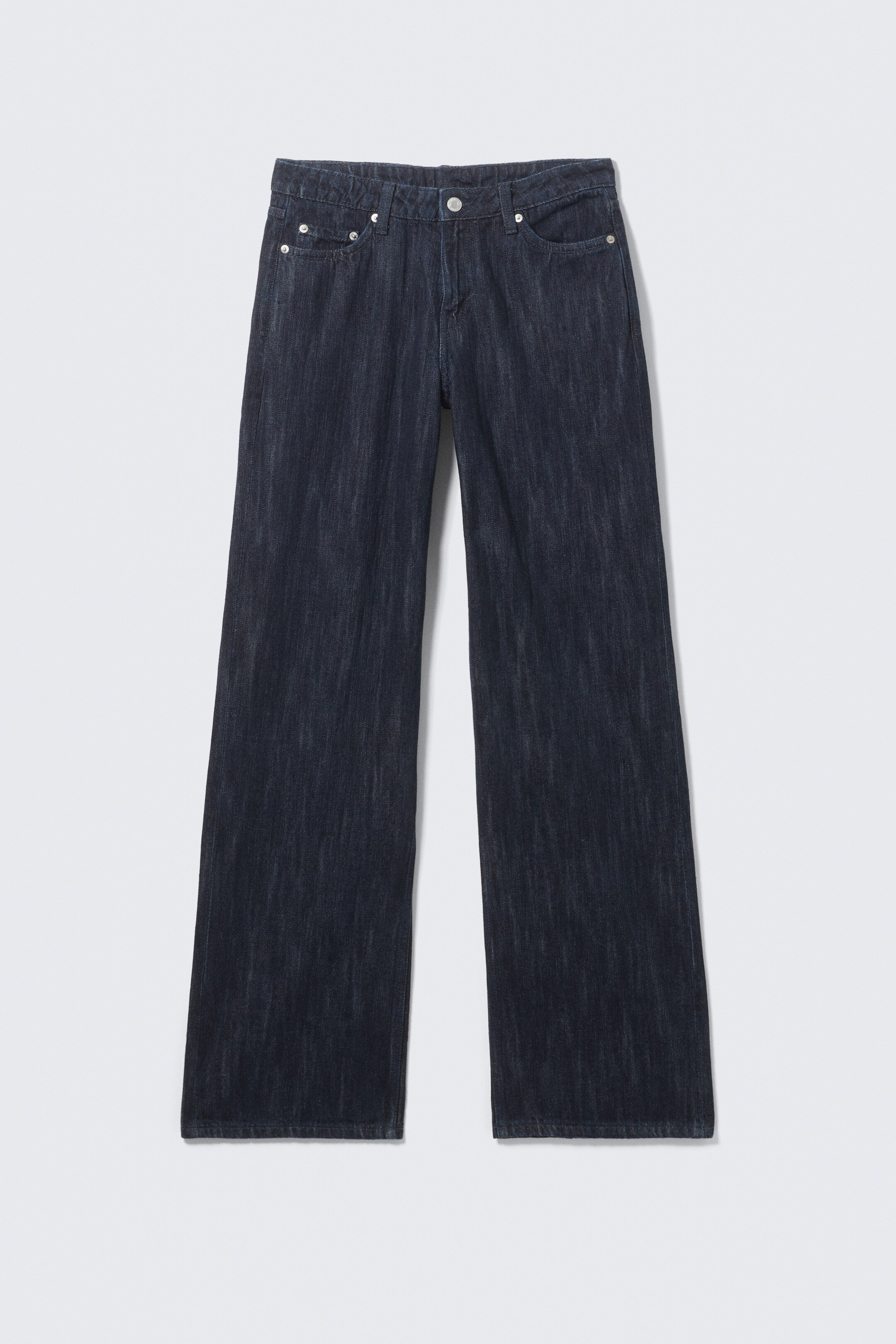 Grotere afbeelding bekijken: Een paar donkere, verticaal vervaagde denim jeans wordt van voren getoond, met een wijde pijp, een knoopsluiting aan de tailleband en voorzakken met zichtbare klinknagels.