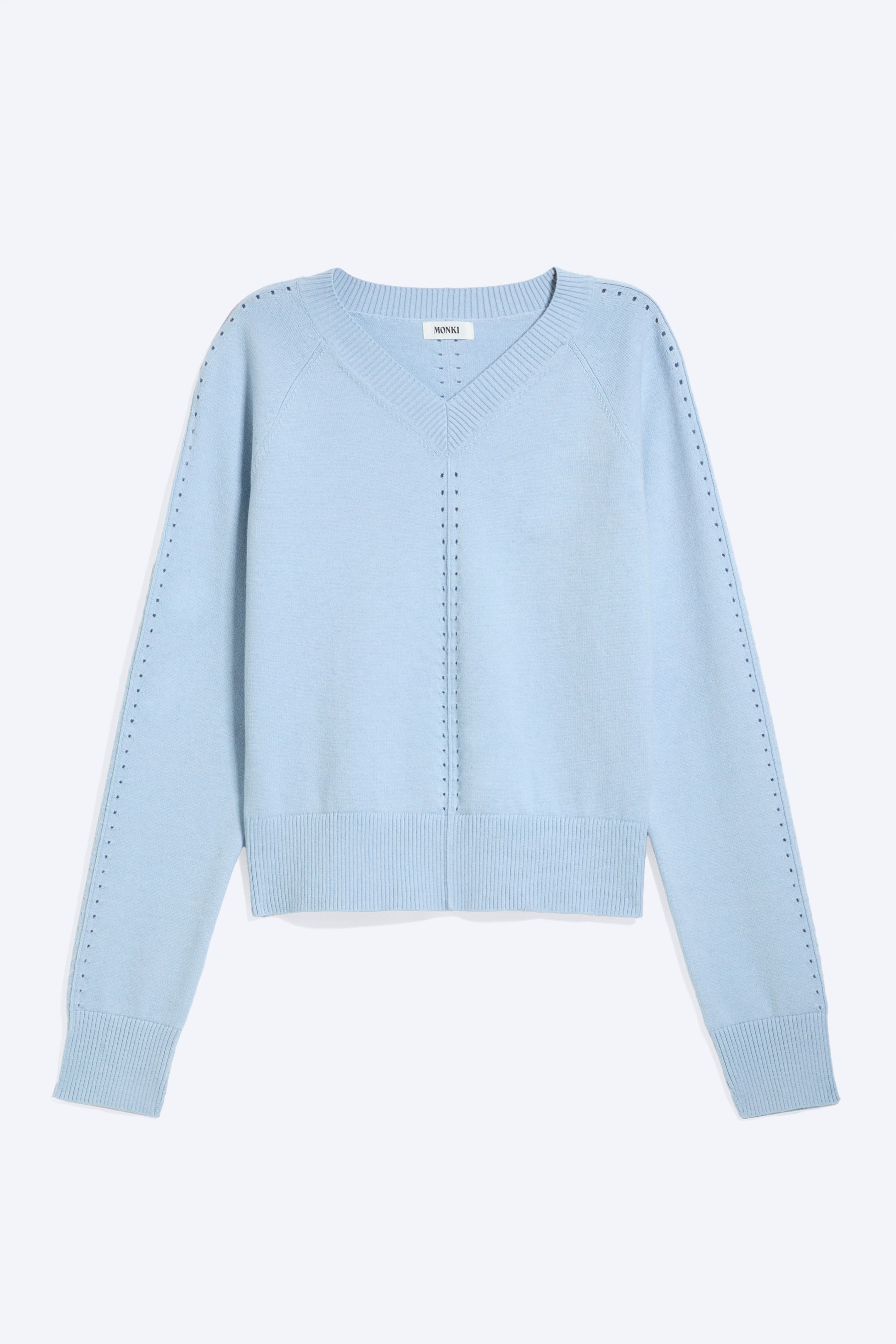 View larger image: A light blue V-neck jumper is showcasing its front. It features a ribbed V-neck, ribbed cuffs, and a ribbed hem, with small perforations forming a vertical line down the centre front and along the outer sides of the raglan sleeves.