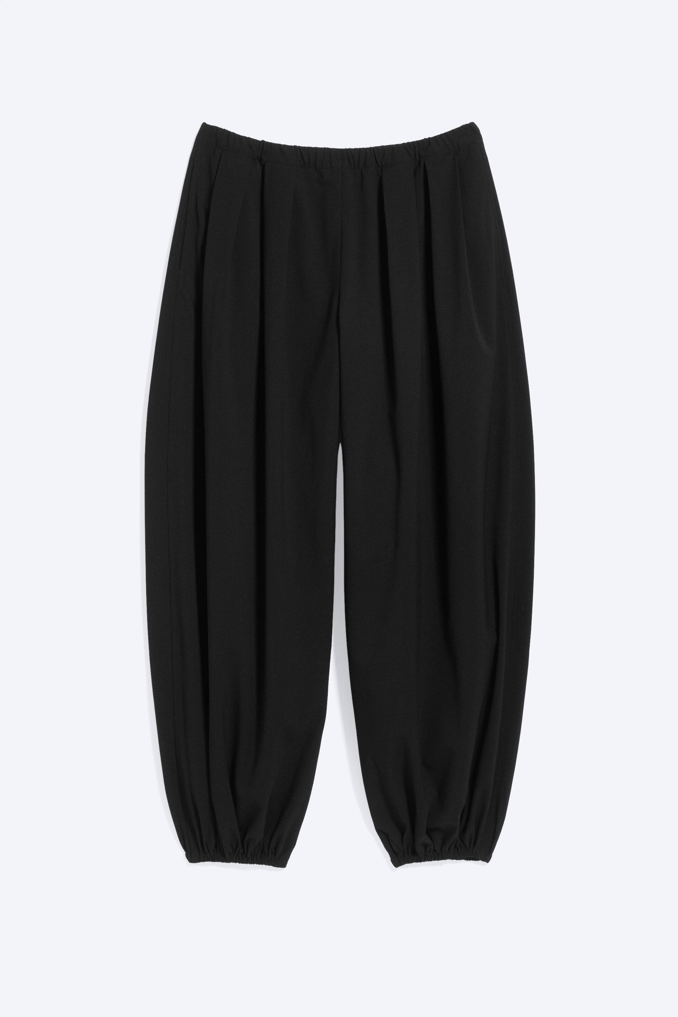 Visualizza immagine più grande: Pantaloni neri con cintura elasticizzata e arricciature sotto la vita, caratterizzati da una forma della gamba voluminosa che si restringe verso i polsini elasticizzati alle caviglie.