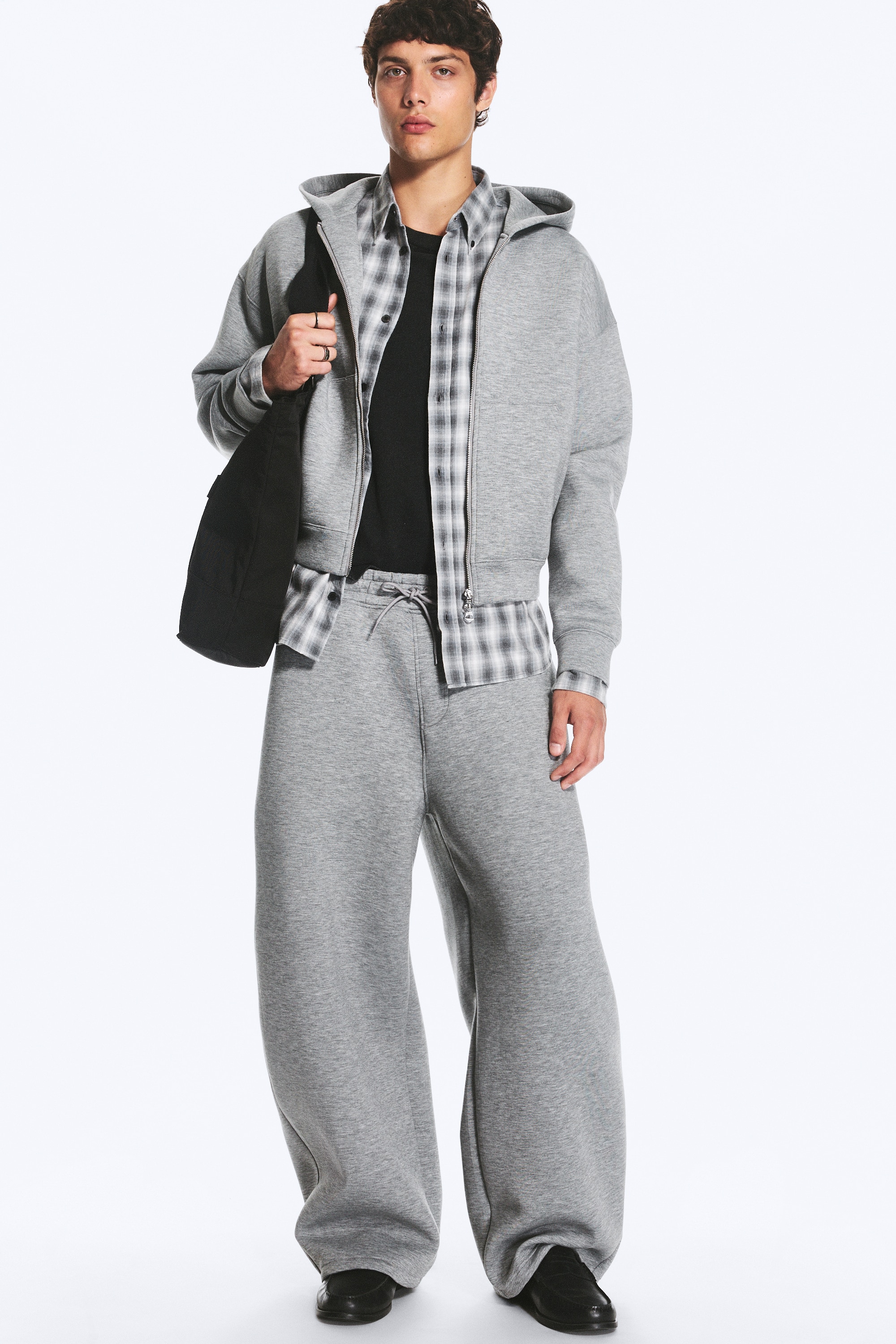 The Cody scuba sweatpants are shown in a front view, featuring a heather grey colour, a relaxed wide-leg silhouette, and an elasticated waistband with a matching drawstring. The design incorporates side slip pockets and adjustable toggle drawcords at the wide hems.