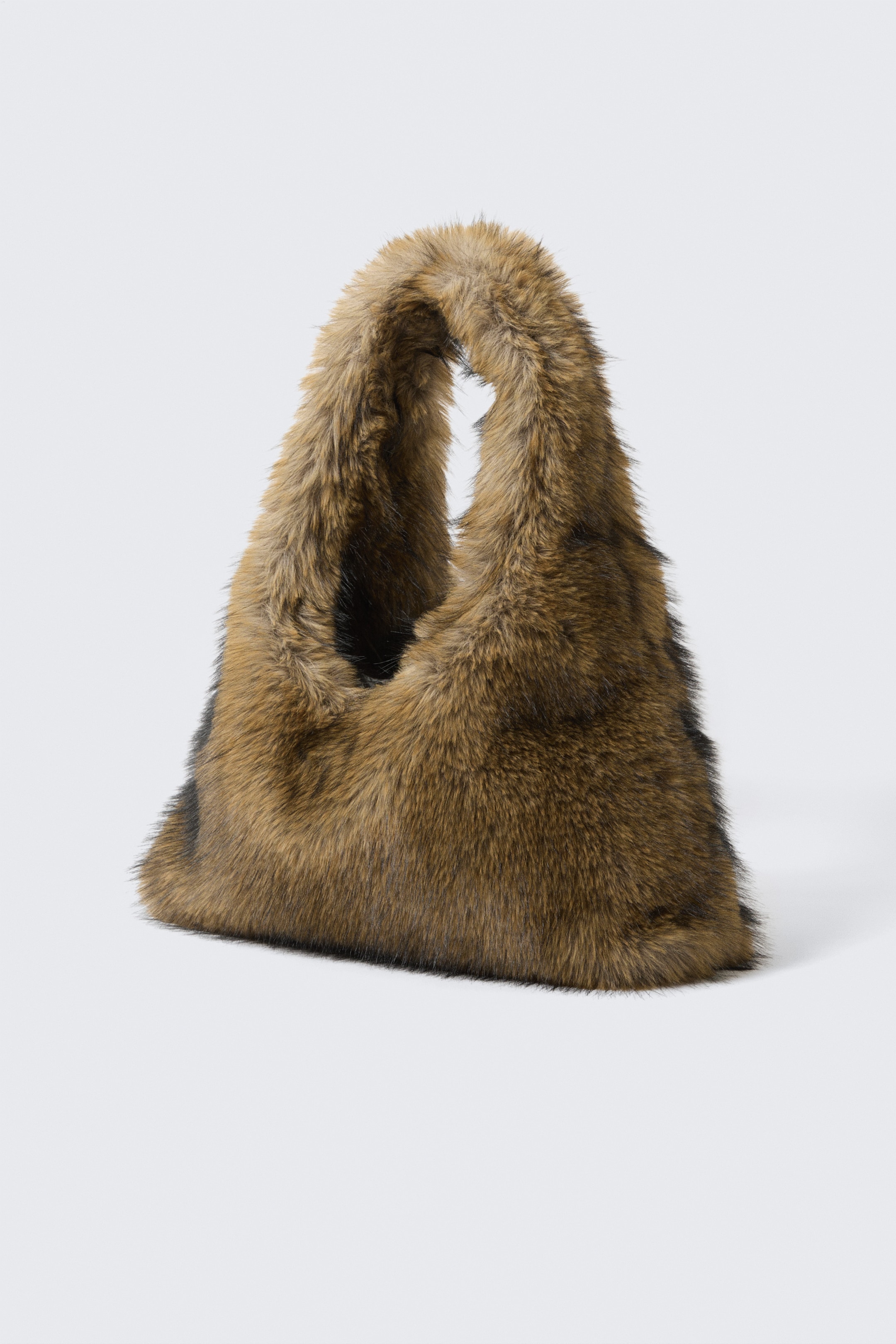 Größeres Bild ansehen: Eine braun melierte Felltasche steht da und präsentiert eine weiche, lässige Form mit einem breiten, integrierten Griff, der eine Öffnung an der Oberseite bildet.