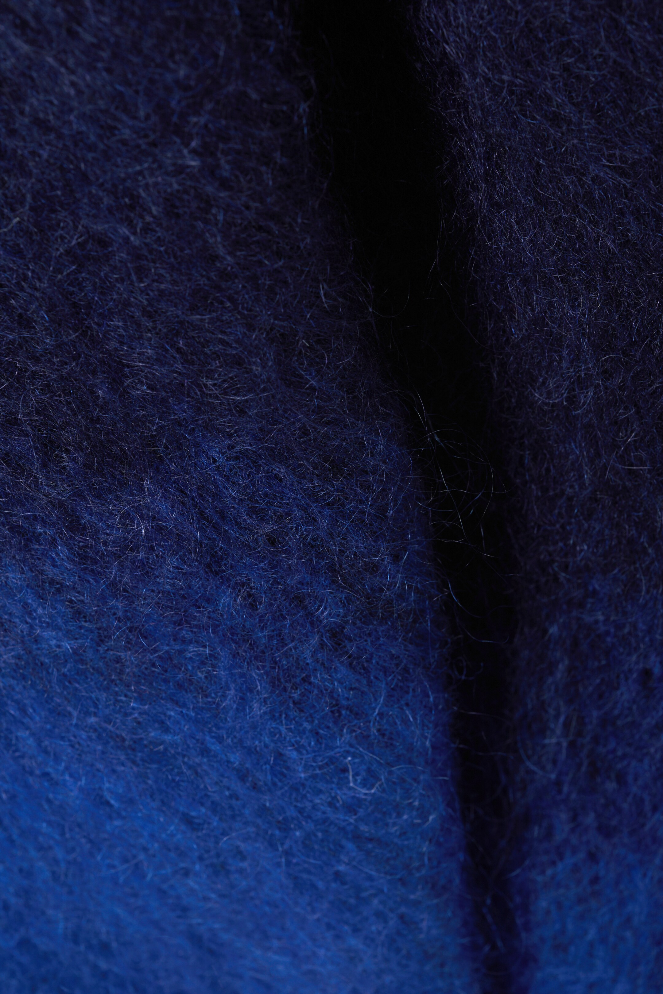 Vezi imaginea mai mare: Un material textil pufos prezintă un efect ombre, trecând de la un albastru marin închis la un albastru regal vibrant, cu fibre lungi care creează o textură moale și un pliu vertical subtil care se desfășoară pe mijloc.