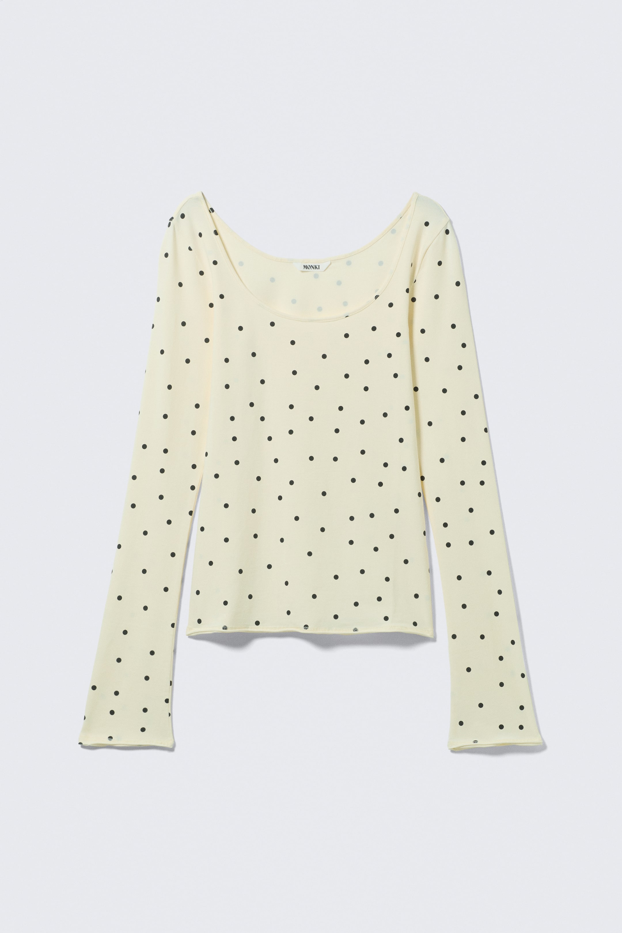Agrandir l'image: Un haut à manches longues est présenté de face, arborant une base jaune pâle avec un motif de pois noirs sur l'ensemble, un décolleté arrondi et des ourlets subtils en point de surjet aux poignets et à l'ourlet inférieur.
