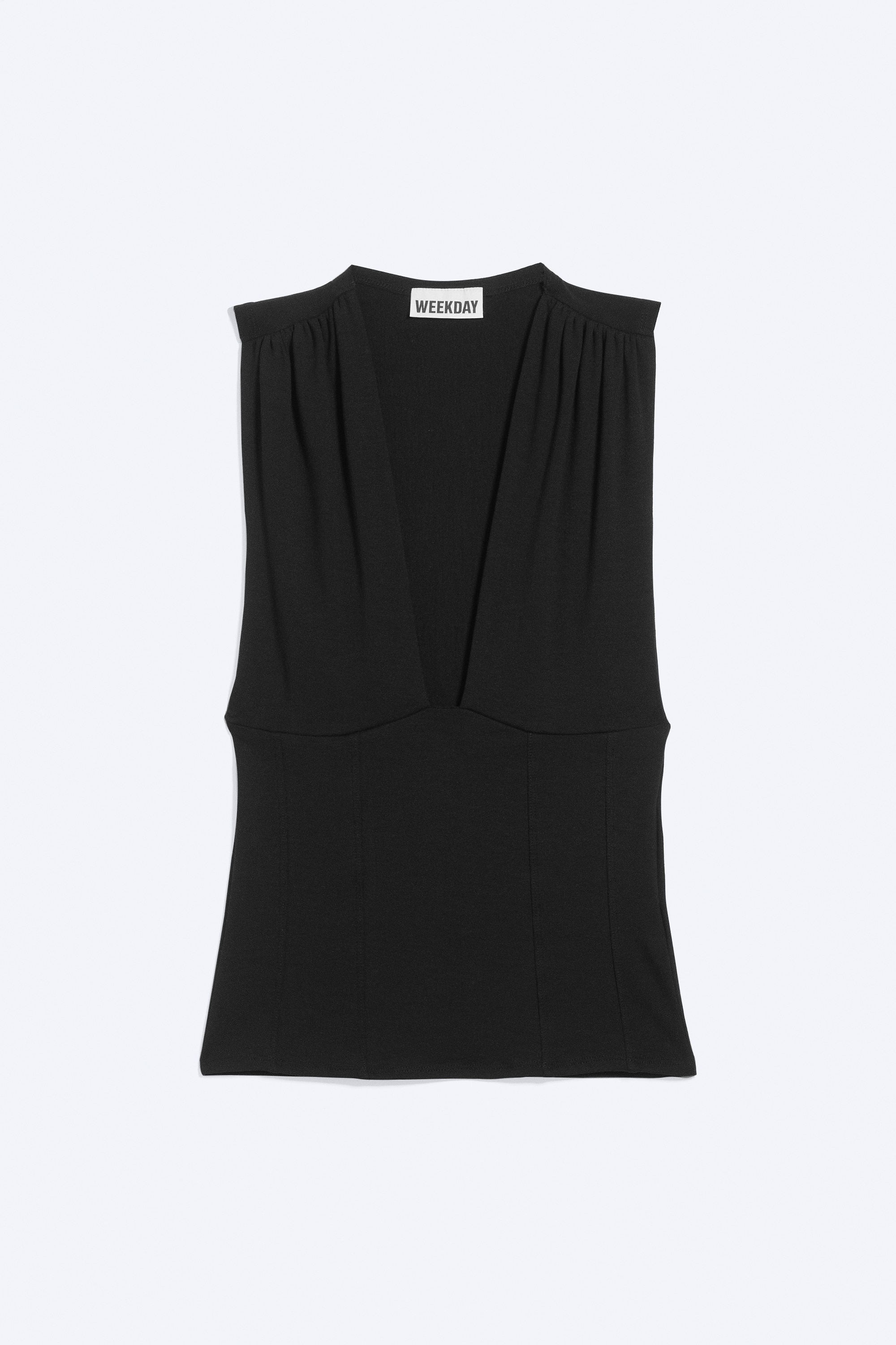 La modella indossa un top corsetto nero aderente, senza maniche, con profonda scollatura a V, spalle arricciate e cuciture sagomate a pannelli. Il top Ã¨ abbinato a jeans blu a vita bassa effetto vissuto e a una cintura scura.