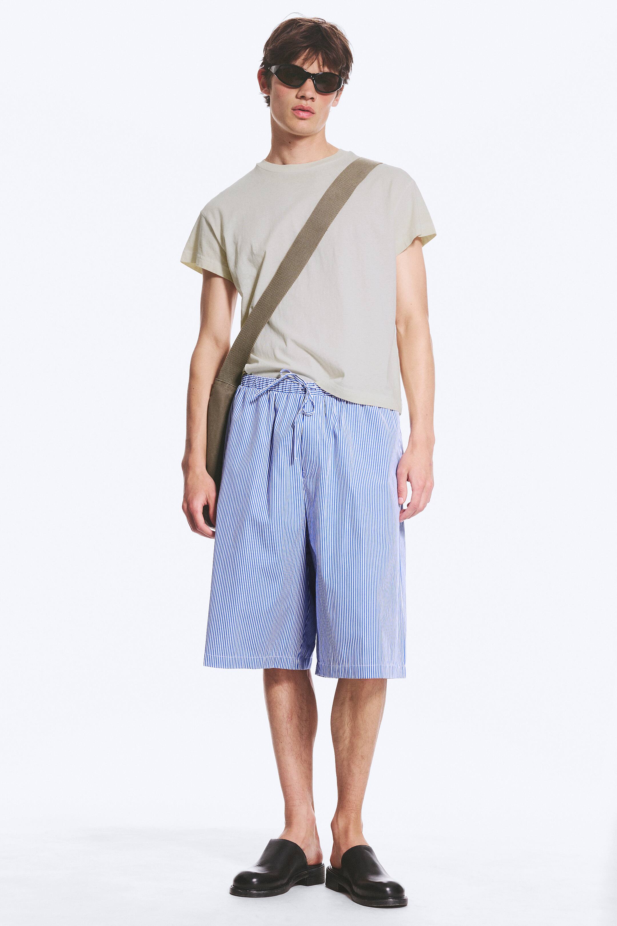 Ver imagen más grande: Shorts a rayas azules y blancas con cintura elástica y cordón, presentan un ajuste relajado de pierna ancha que termina por encima de las rodillas.