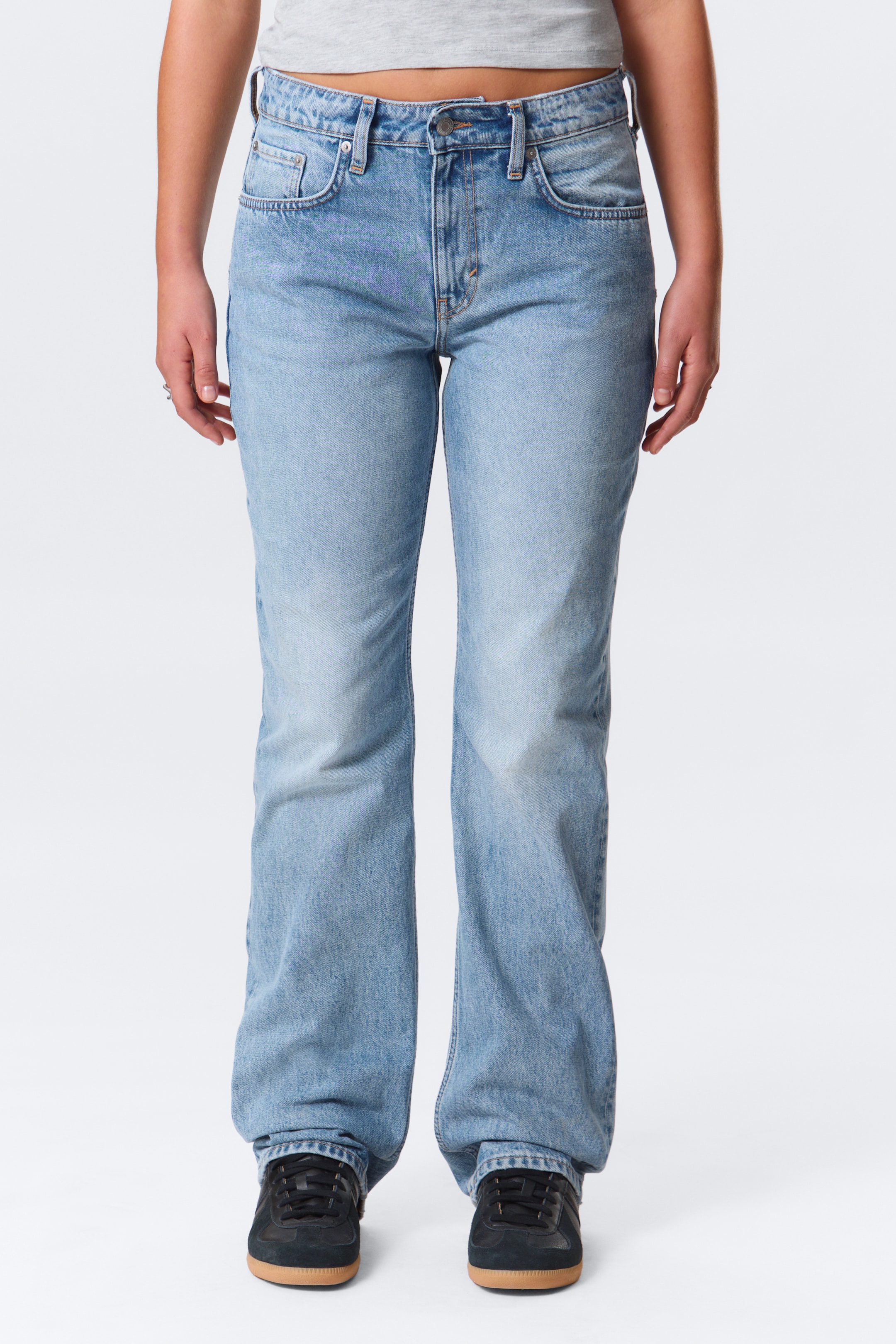 Grotere afbeelding bekijken: Licht gewassen blauwe denim jeans staan naar voren, met een relaxte pasvorm die subtiel wijder wordt aan de enkels. Ze hebben een vijf-zakkenstijl met zichtbare riemlussen en een knoop- en ritssluiting aan de voorkant, terwijl ze ook natuurlijke vervaging vertonen op de dijen en knieën.