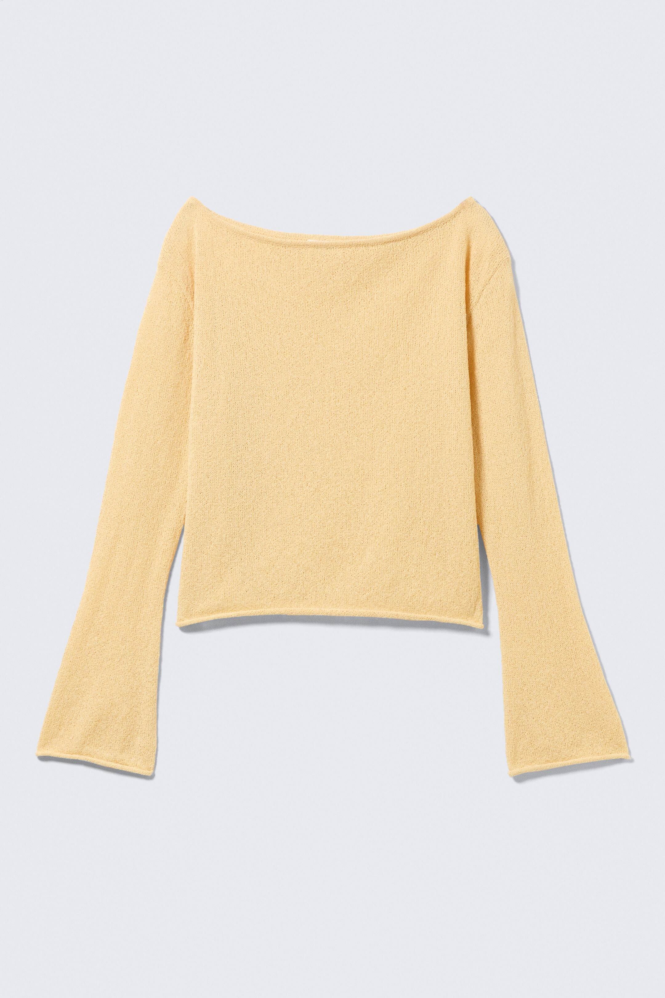 Größeres Bild anzeigen: Ein blassgelber Strickpullover präsentiert seine VORDERSEITE, mit einem Bootsausschnitt und langen, ausgestellten Glockenärmeln. Der verkürzte Pullover zeigt einen unvollendeten Saum.