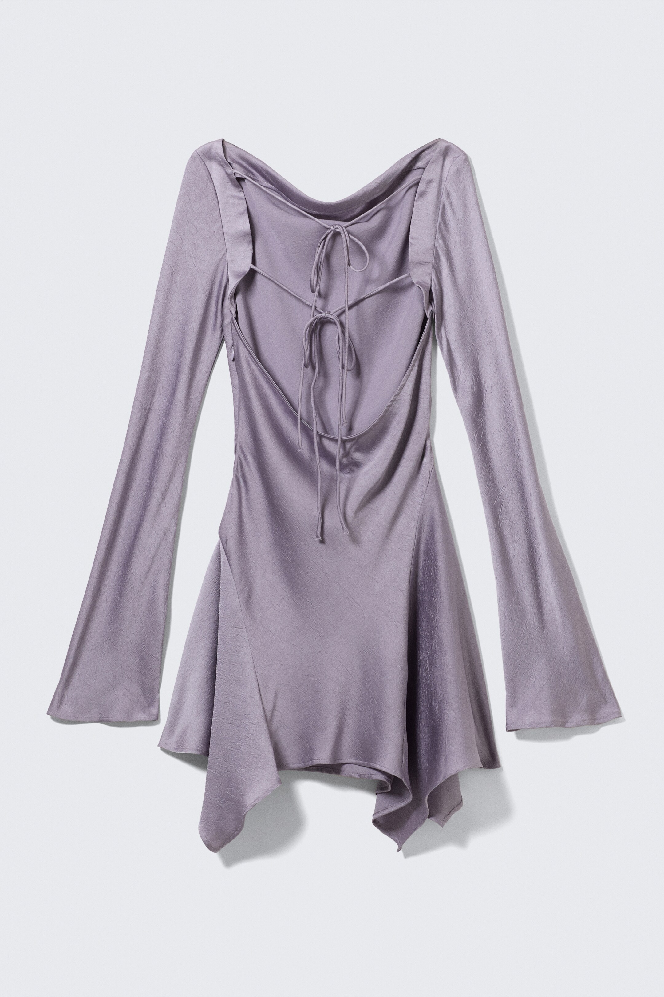 View larger image: A lilac satin mini dress is presenting its back view, featuring a textured, slightly crinkled finish. The dress is showcasing a deep cowl neckline with multiple criss-crossing ties, long bell sleeves, and an asymmetrical draped hemline.