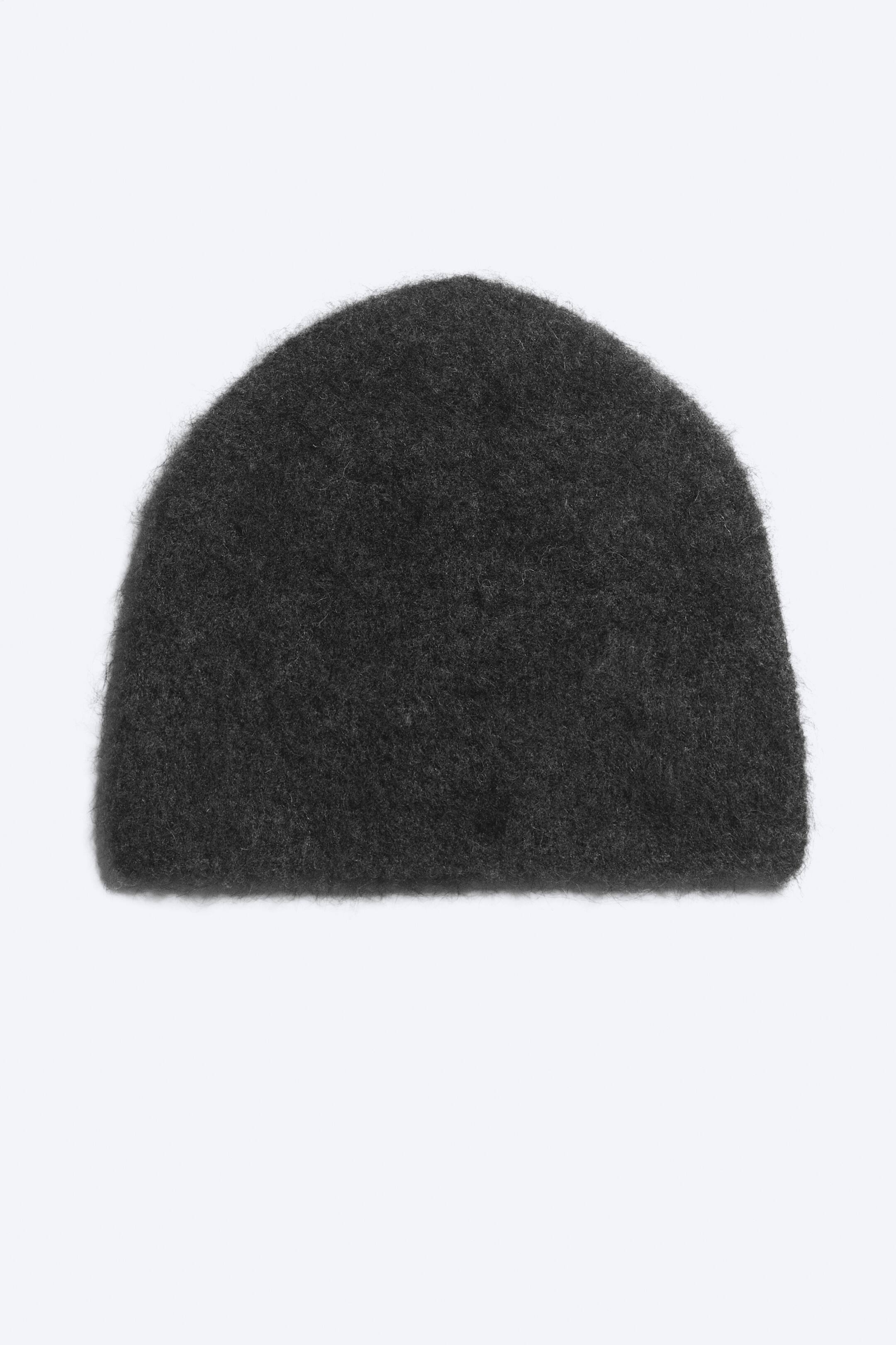 View larger image: A dark grey knitted beanie is shown front-on, featuring a soft, fuzzy texture and a simple, rounded dome shape with a neat edge.