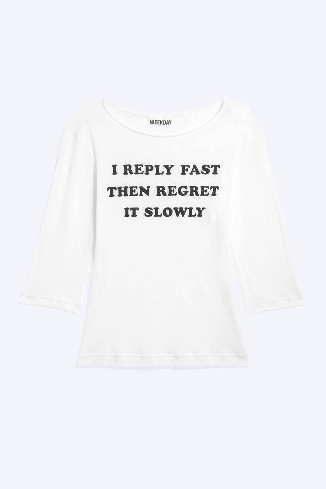 Uma camisola branca de manga trÃªs quartos estÃ¡ virada para a frente, exibindo um decote barco largo e texto preto impresso no peito com a frase: "I REPLY FAST THEN REGRET IT SLOWLY." - 1