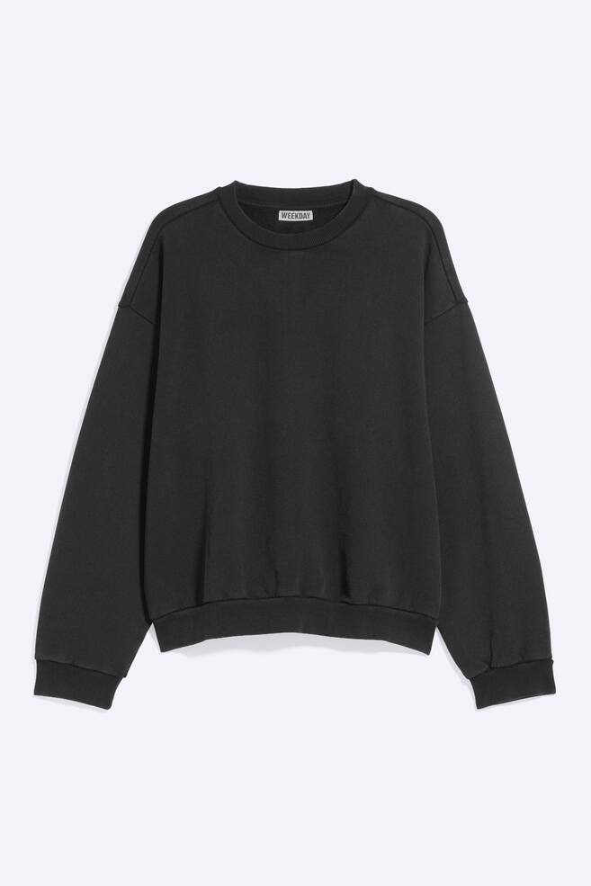 Ein locker geschnittener schwarzer Sweatshirt ist von vorne zu sehen und verfÃ¼gt Ã¼ber einen Rundhalsausschnitt, Ã¼berschnittene Schultern sowie gerafftes Volumen an Ãrmeln und KÃ¶rper. Das KleidungsstÃ¼ck ist mit gerippten AbschlÃ¼ssen am Halsausschnitt, an den ÃrmelbÃ¼ndchen und am Saum versehen. - 1
