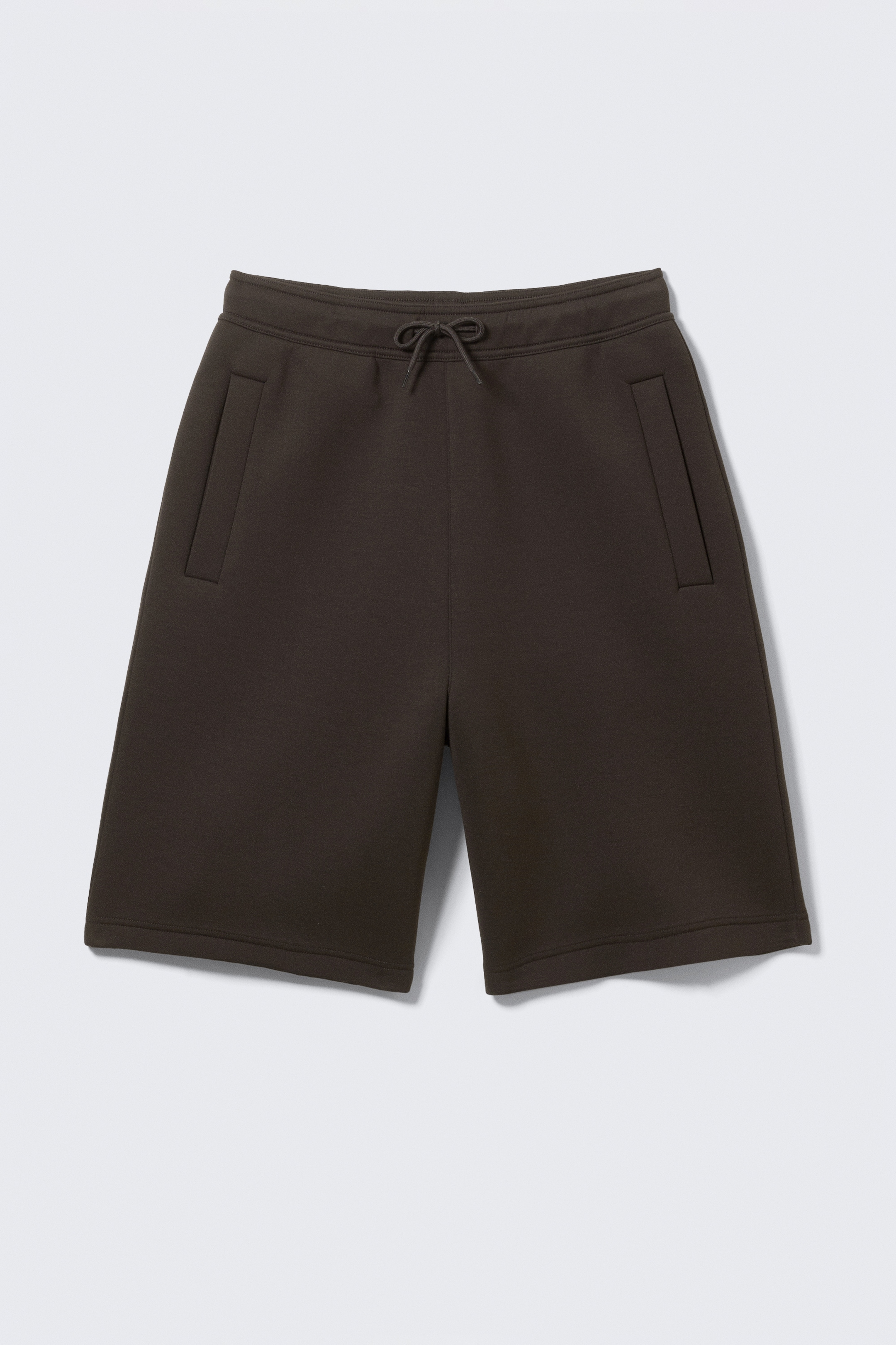 Agrandir l'image: Des shorts marron foncé sont posés à plat, face avant. Ils présentent une taille élastiquée avec un cordon de serrage noué et deux poches latérales insérées, et sont faits d'un tissu lisse et structuré s'étendant juste au-dessus du genou.