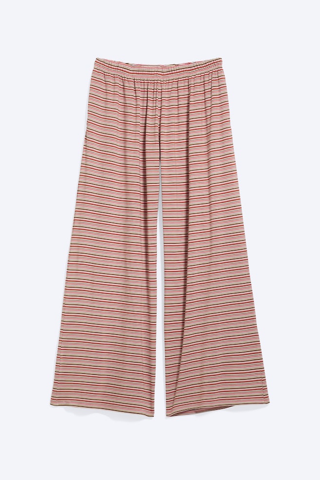 Un par de pantalones de pierna ancha se presenta en vista frontal, con rayas horizontales en rojo, rosa y oliva, y una cintura elástica fruncida. - 1