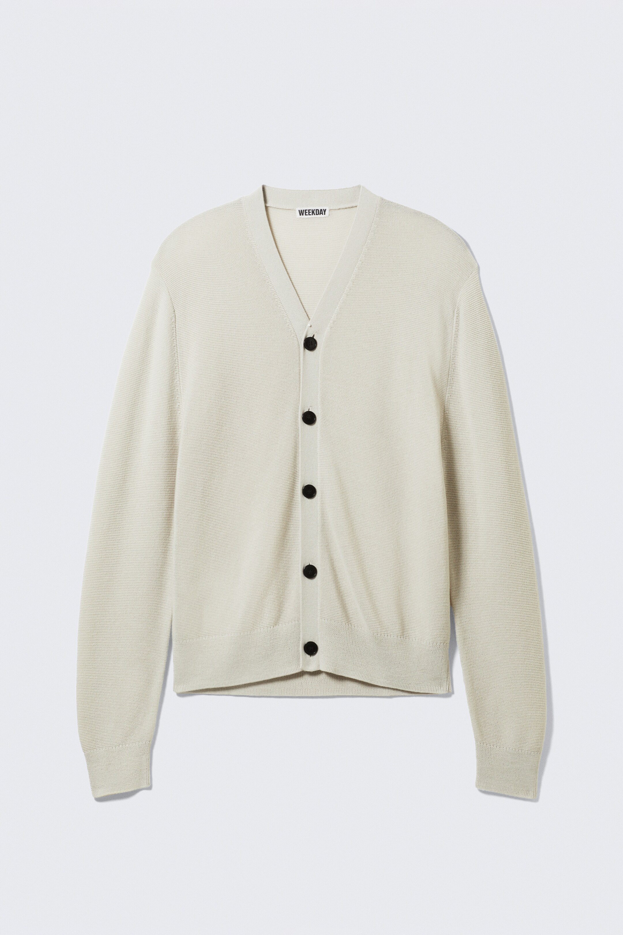 Visualizza immagine più grande: Un cardigan in maglia a trama fine di colore beige chiaro è rivolto in avanti, mostrando uno scollo a V e una chiusura frontale a bottoni con sei bottoni circolari neri. Presenta maniche lunghe con polsini a coste e un orlo inferiore a coste.