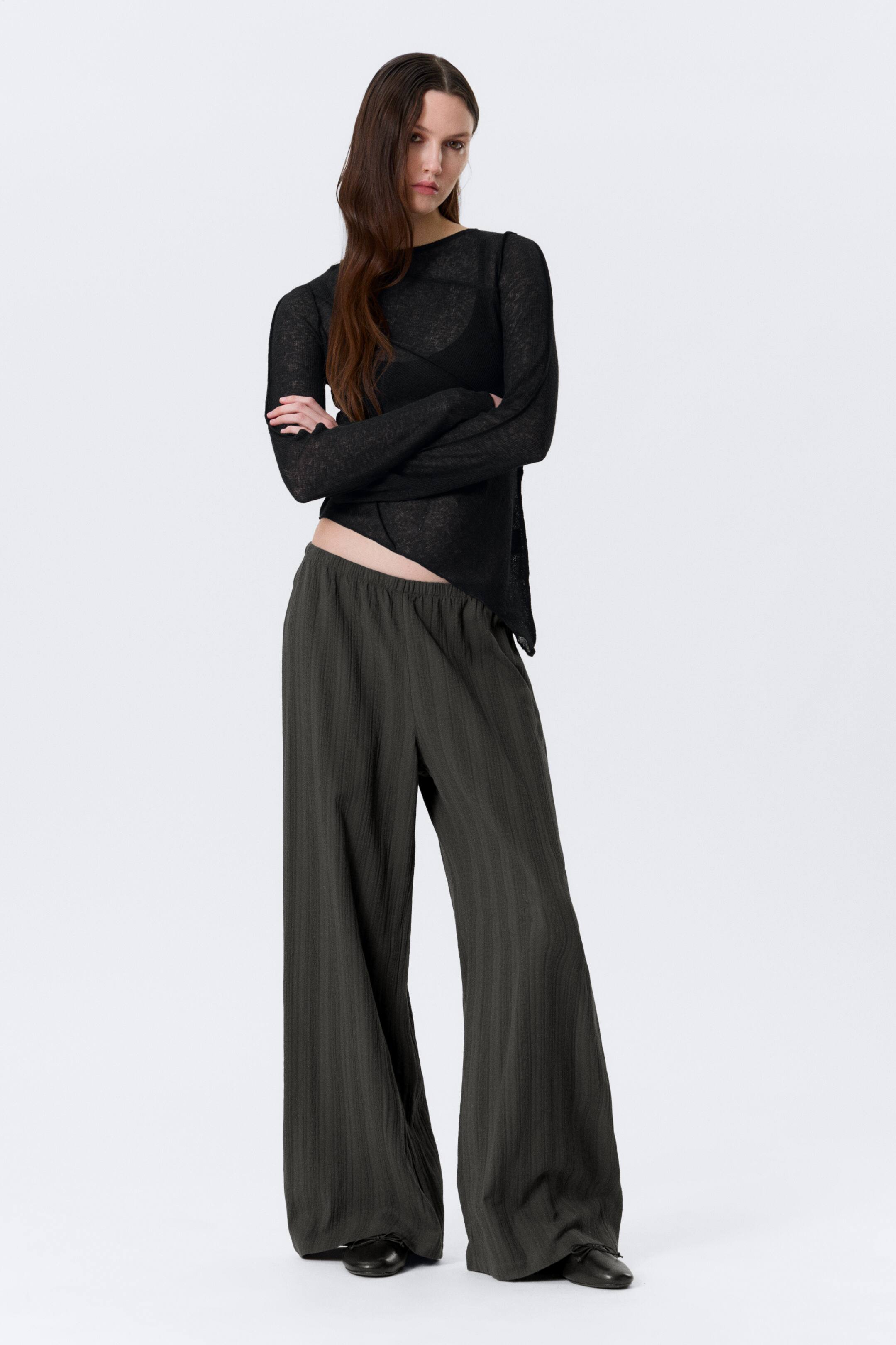 Visa större bild: De mörkgröna byxorna med vida ben har en elastisk midja och en subtil vertikal texturväv, vilket ger en lös och flödande passform.