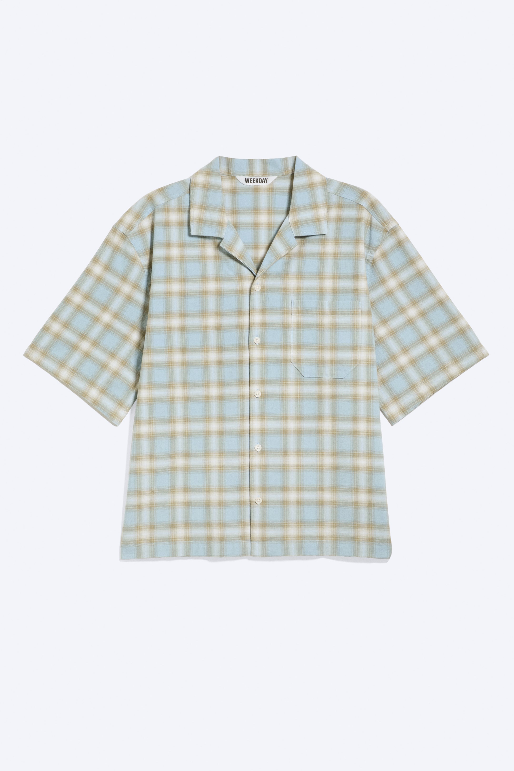 Agrandir l'image: Une chemise à manches courtes à carreaux est présentée de face, arborant un motif à carreaux bleu clair, beige et blanc. Elle est dotée d'un col camp avec une étiquette de marque visible 'WEEKDAY', d'une fermeture boutonnée complète à l'avant et d'une poche plaquée unique sur la poitrine gauche.