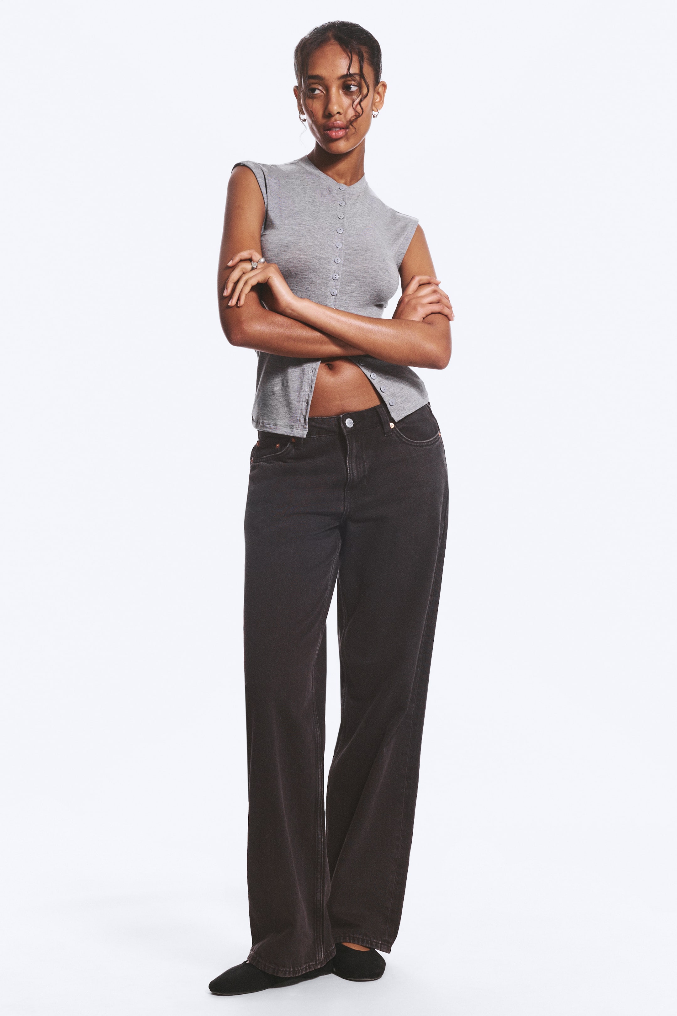 View larger image: The grey knit top is angled slightly to the right, showcasing a V-neckline, structured cap sleeves, and a full button-front fastening with small, matching buttons, with the lower buttons left undone and cropped above the waist of dark jeans.