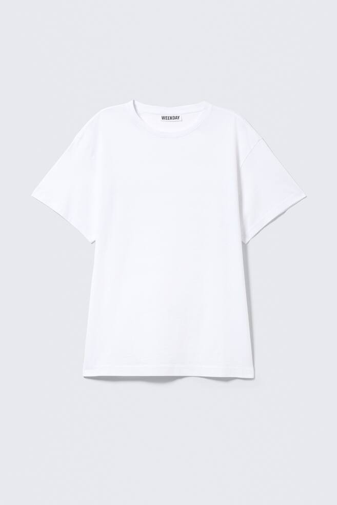 Een wit T-shirt met korte mouwen toont zijn voorkant, met een ronde halslijn en rechte zoom. Het 'WEEKDAY' merklabel is zichtbaar aan de binnenkant van de achterste kraag. - 1