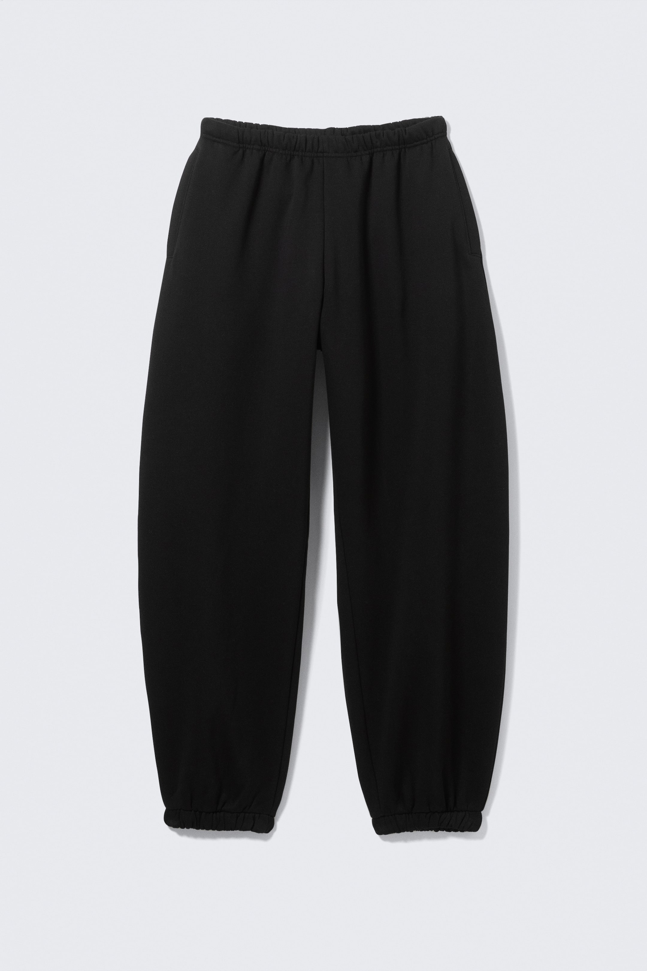 Agrandir l'image: Un pantalon de survêtement noir est présenté de FACE, affichant une coupe ample avec une taille élastiquée, des poches passepoilées latérales et des poignets élastiqués.