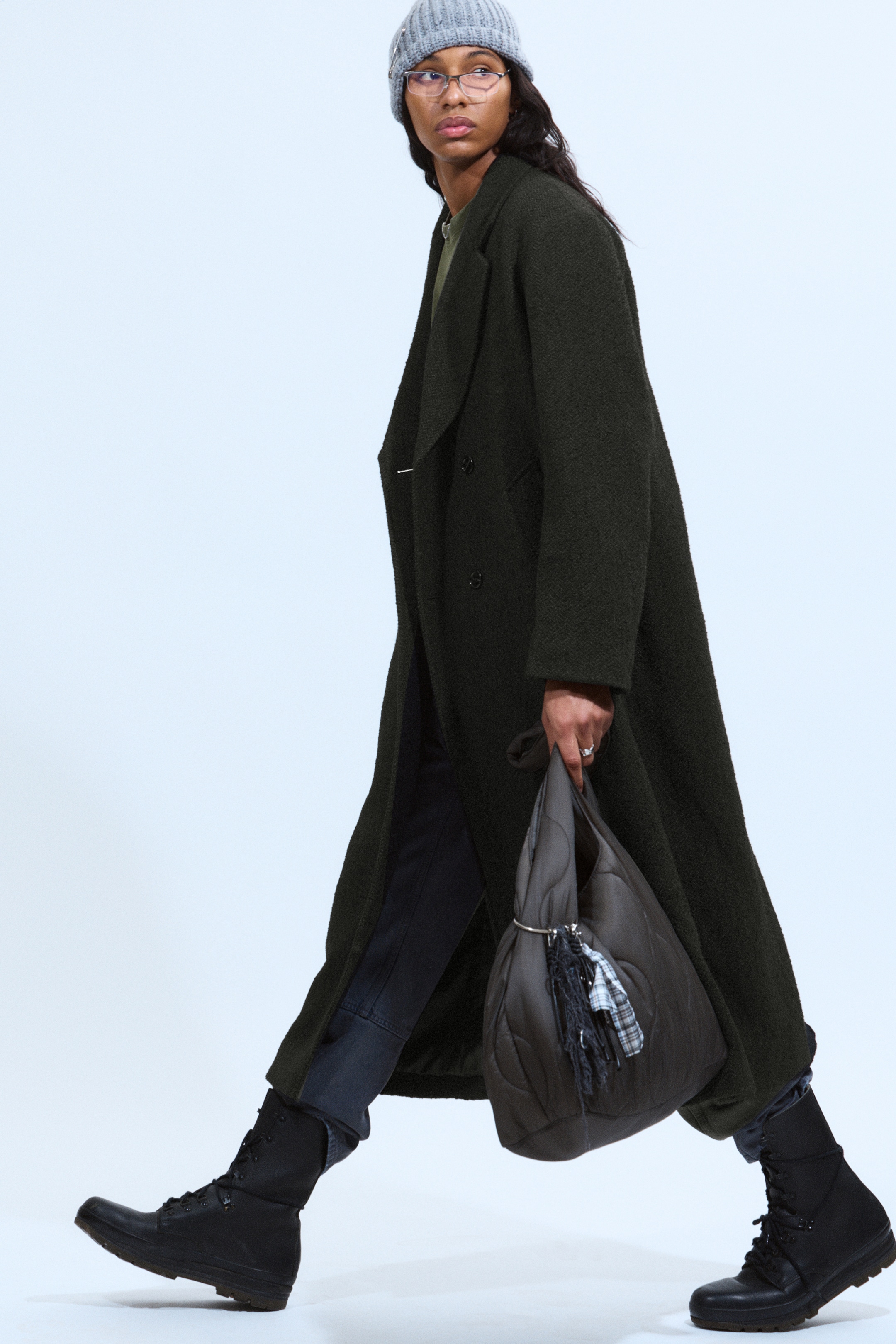 Ingrandisci l'immagine: Un cappotto doppiopetto verde scuro, con una texture particolare, viene presentato, caratterizzato da ampi revers a lancia e una vestibilità oversize a tutta lunghezza. È mostrato dal lato anteriore sinistro, mettendo in evidenza la sua ampia silhouette e la caduta rilassata.