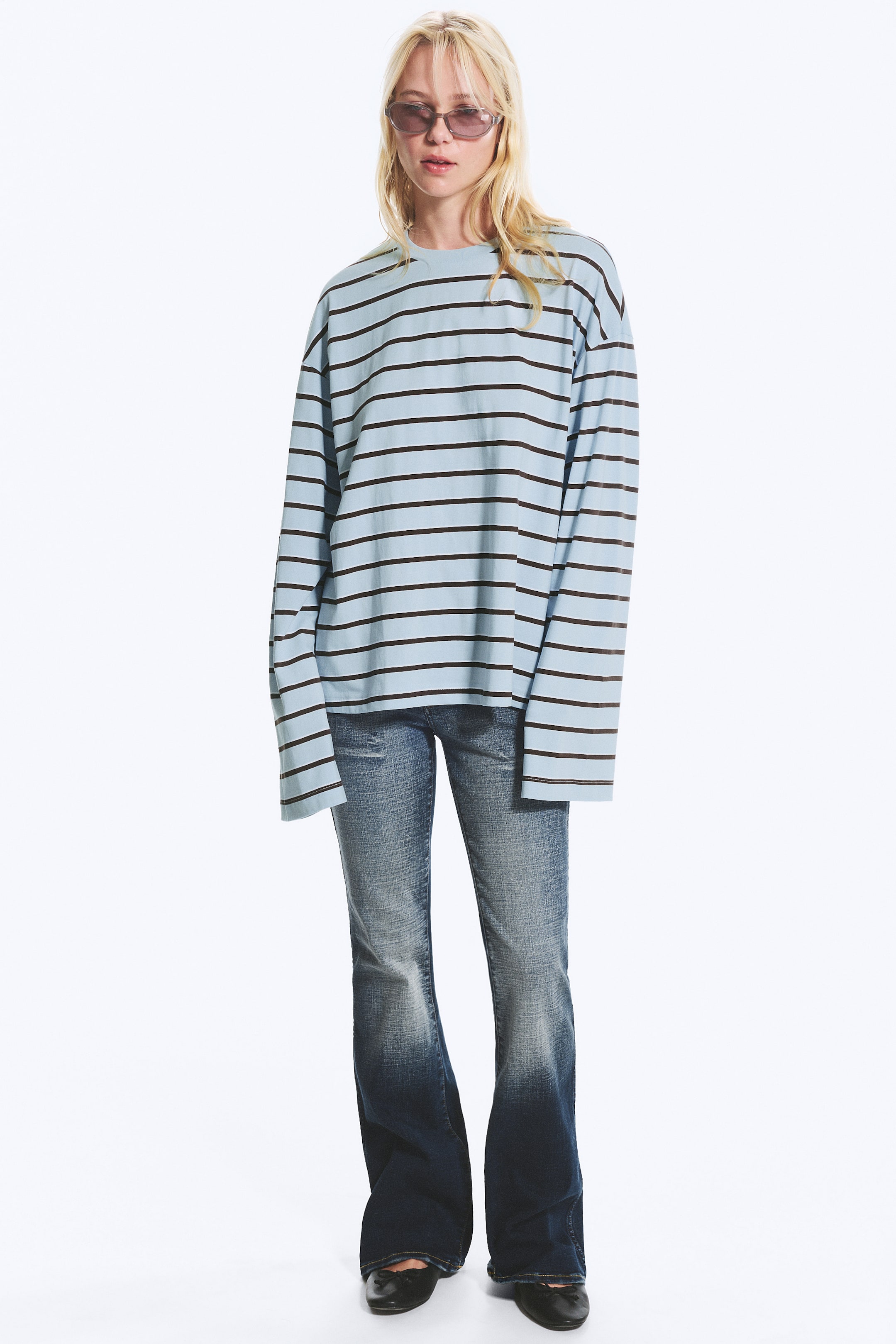 Agrandir l'image: Une chemise à manches longues présente un tissu bleu clair avec des rayures horizontales brun foncé. Elle est conçue avec un col rond et des manches longues et amples, offrant une coupe oversize et un ourlet droit.
