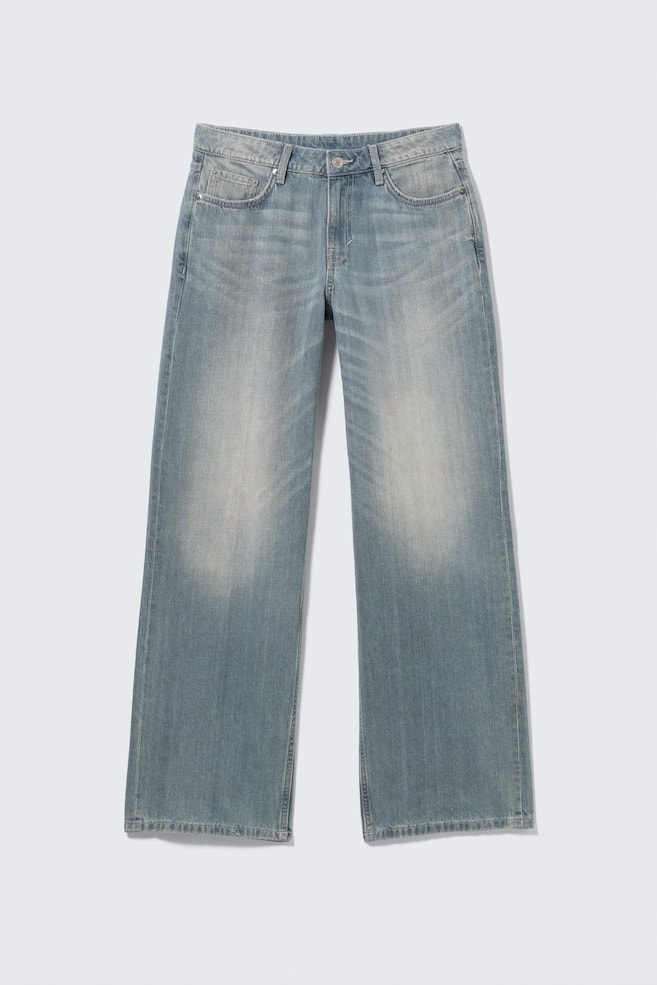 Un jean bleu clair taille basse est présenté de FACE, avec une coupe ample et une jambe large et longue en denim rigide. Le jean arbore un design classique à 5 poches avec une braguette zippée visible, et présente un délavage dégradé, plus clair au niveau des cuisses. - 1
