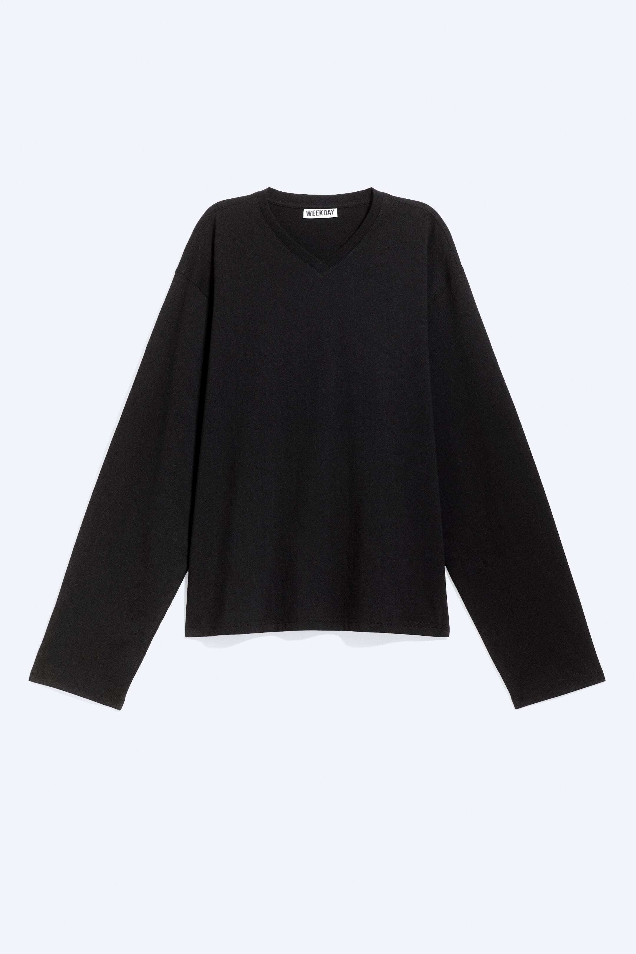 Visualizza l'immagine ingrandita: Una T-shirt nera, dalla linea boxy, con scollo a V e maniche lunghe, è ripresa frontalmente, mostrando una silhouette rilassata con spalle scese e maniche ampie e morbide. Il capo presenta un classico scollo a V e un orlo pulito e diritto.