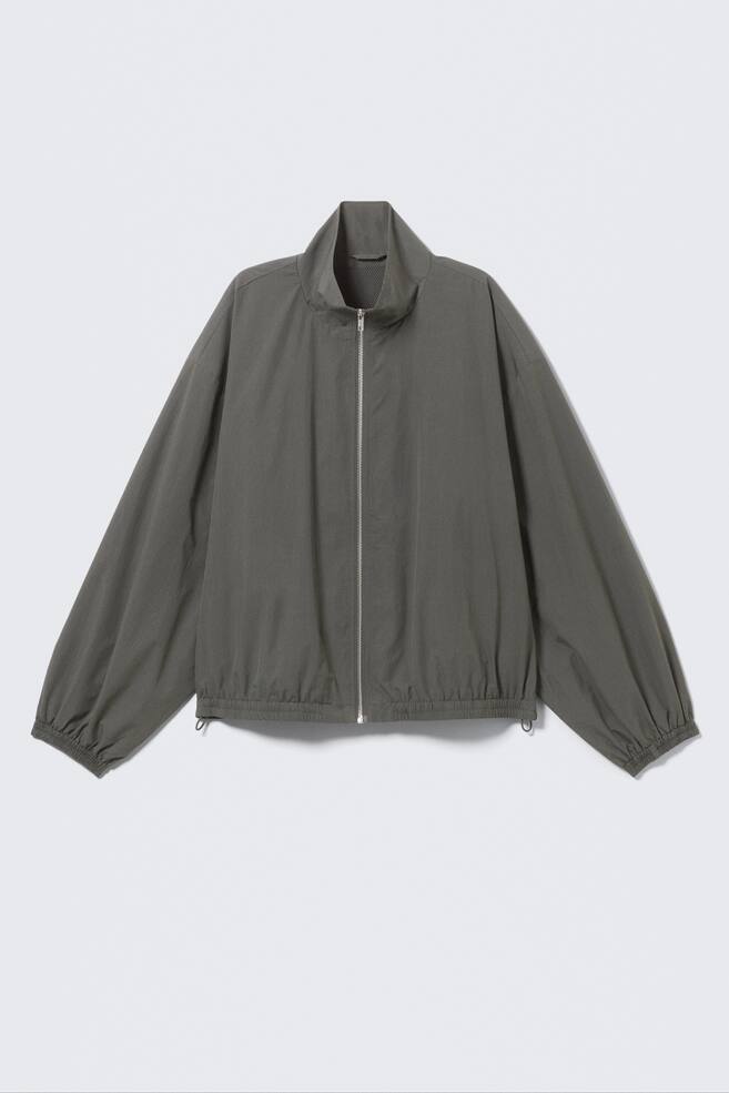 An oversized khaki-green track jacket is shown FRONT, featuring a high collar, a full-length silver-toned zip, elasticated cuffs and an elasticated hem with visible drawstrings. - 1