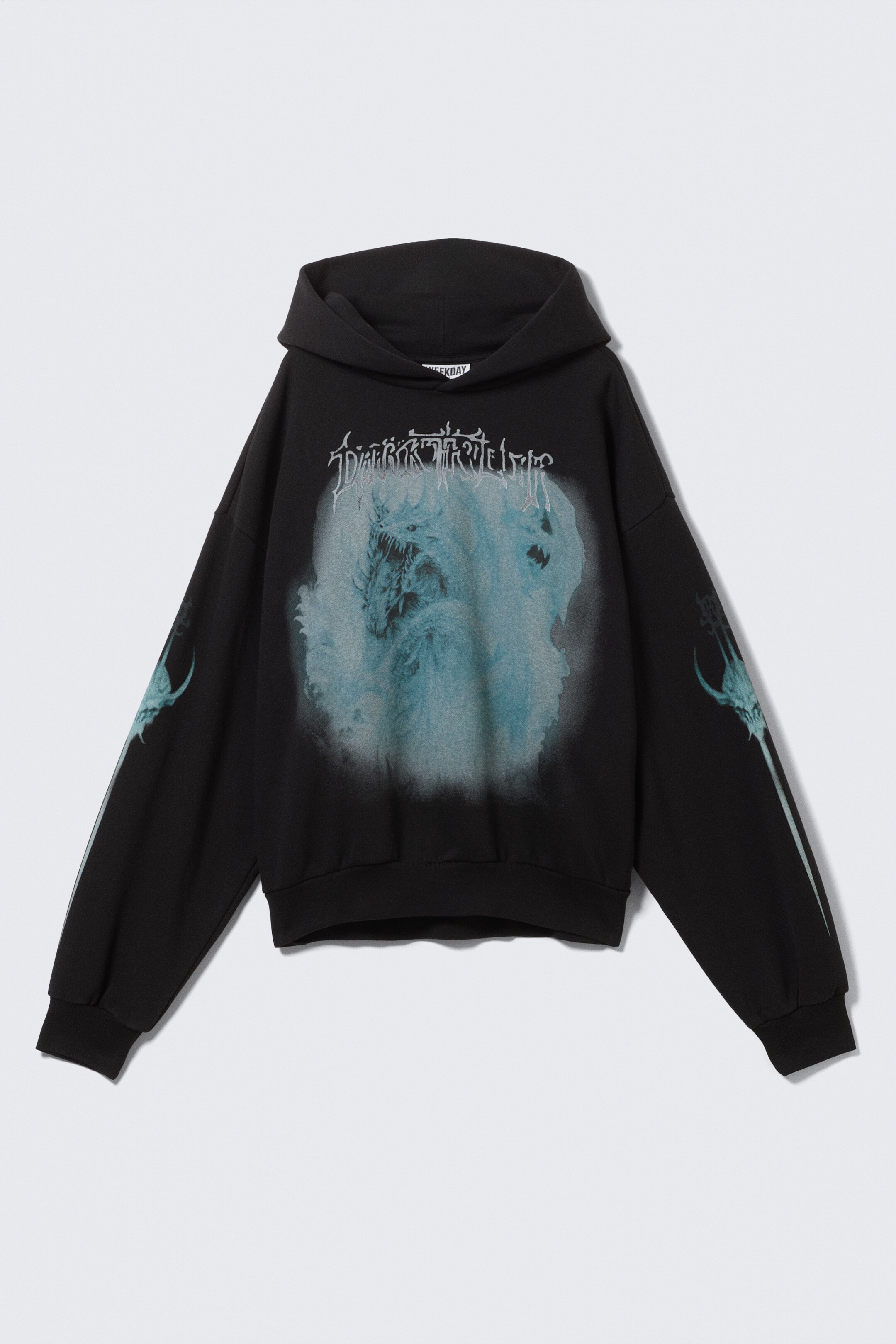 Agrandir l'image: Un sweat à capuche graphique noir présente un grand graphique bleu clair sur le DEVANT, représentant une créature monstrueuse et du texte, ainsi que des graphiques assortis plus petits sur les manches. Il affiche une silhouette ample avec des épaules tombantes, une capuche spacieuse, un ourlet froncé et des poignets côtelés.