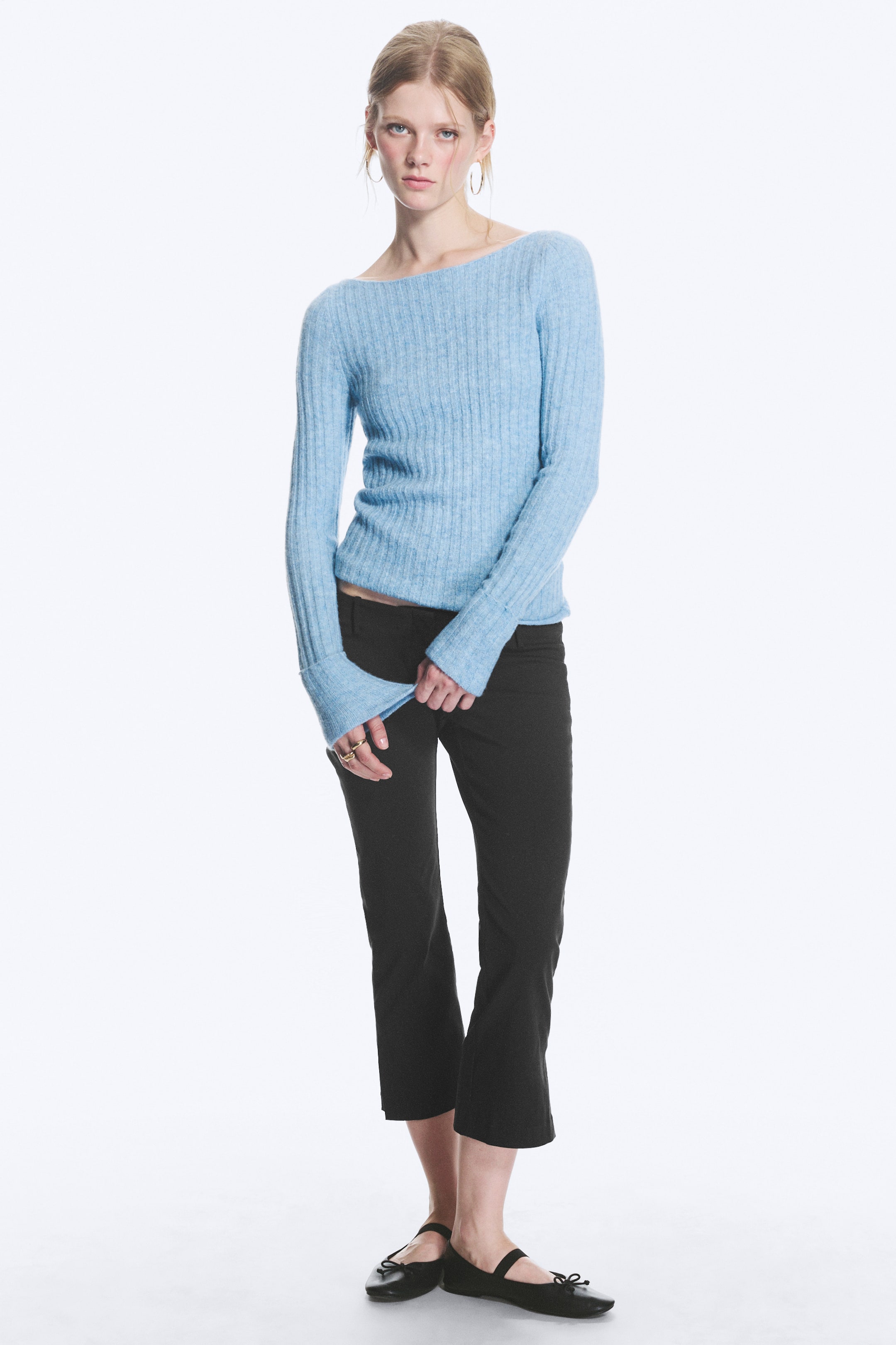 View larger image: The light blue ribbed knit jumper features a wide boat neckline and long sleeves extending over the hands, presenting a slim fit with a slightly fuzzy texture.
