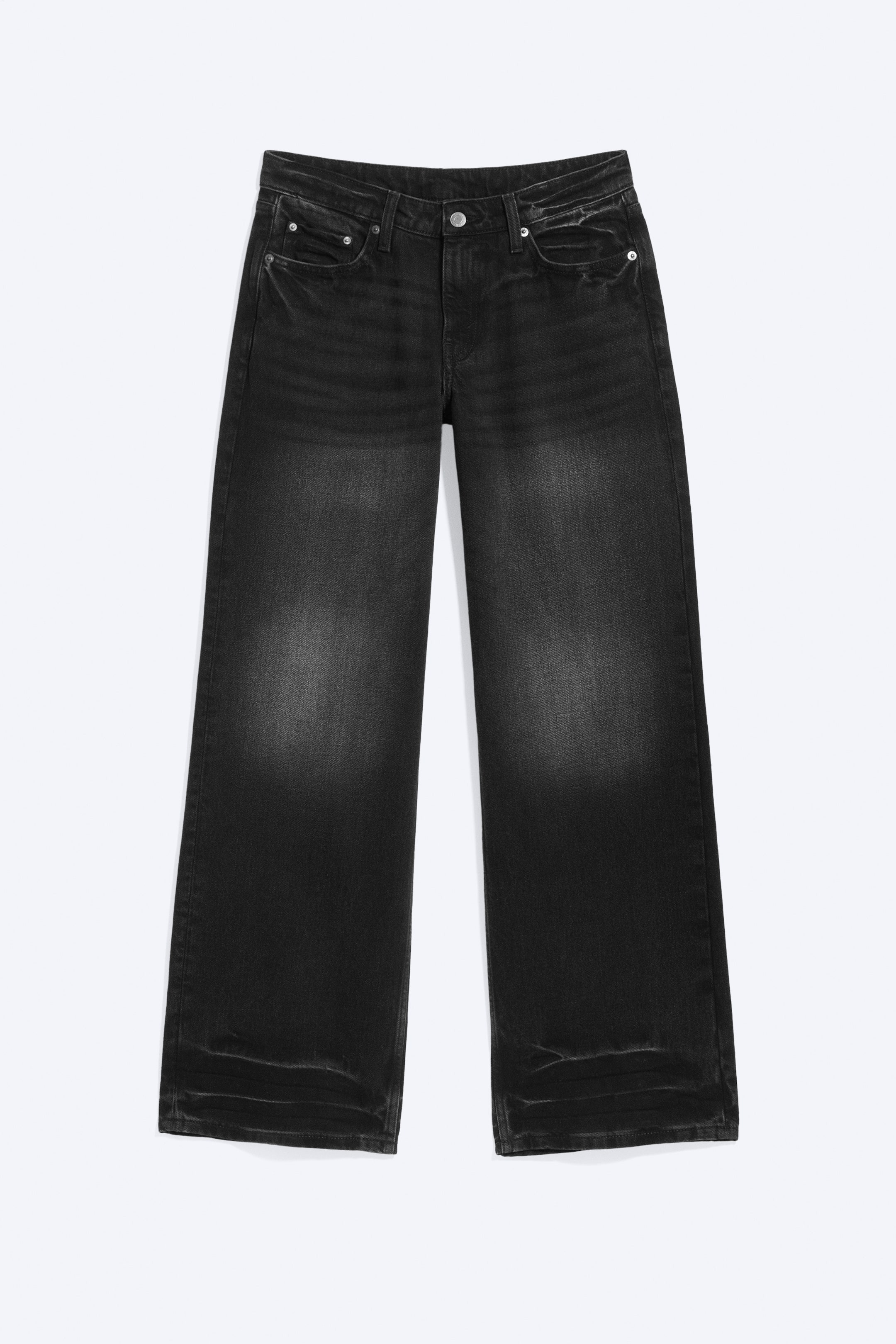 Visualizza l'immagine ingrandita: Questi jeans neri a gamba larga, rivolti in avanti, presentano un lavaggio sbiadito con aree più chiare sulle cosce e lievi segni di usura intorno alle tasche anteriori. Sono caratterizzati da uno stile a cinque tasche con un singolo bottone e chiusura a zip.