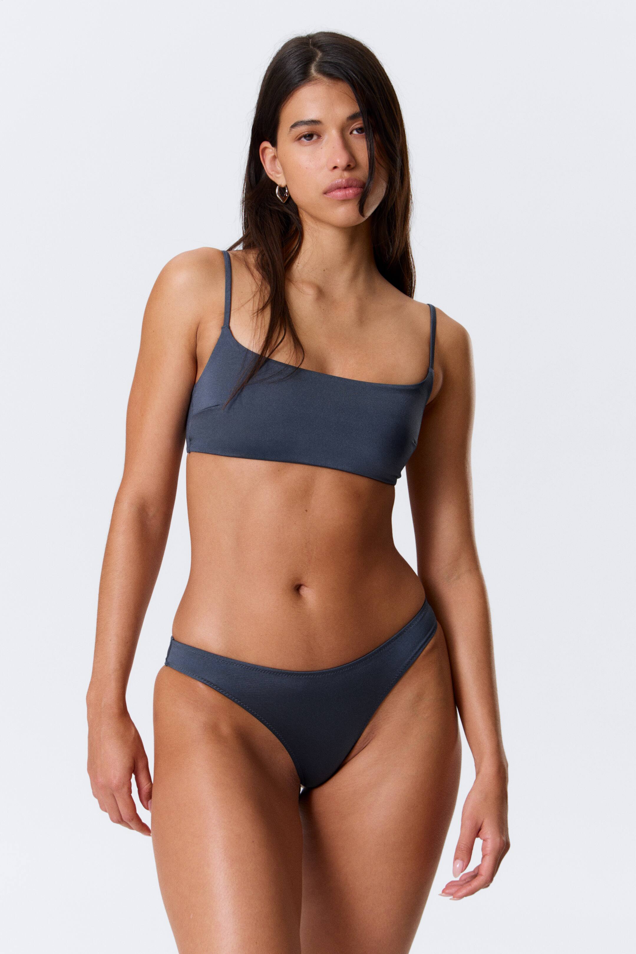 Se større billede: Et mørkegråt todelt badetøj, der fremhæver en firkantet bikini-top med tynde spaghetti-stropper og en højtaljet bikiniunderdel med en V-formet front, præsenteret fra en frontvisning.