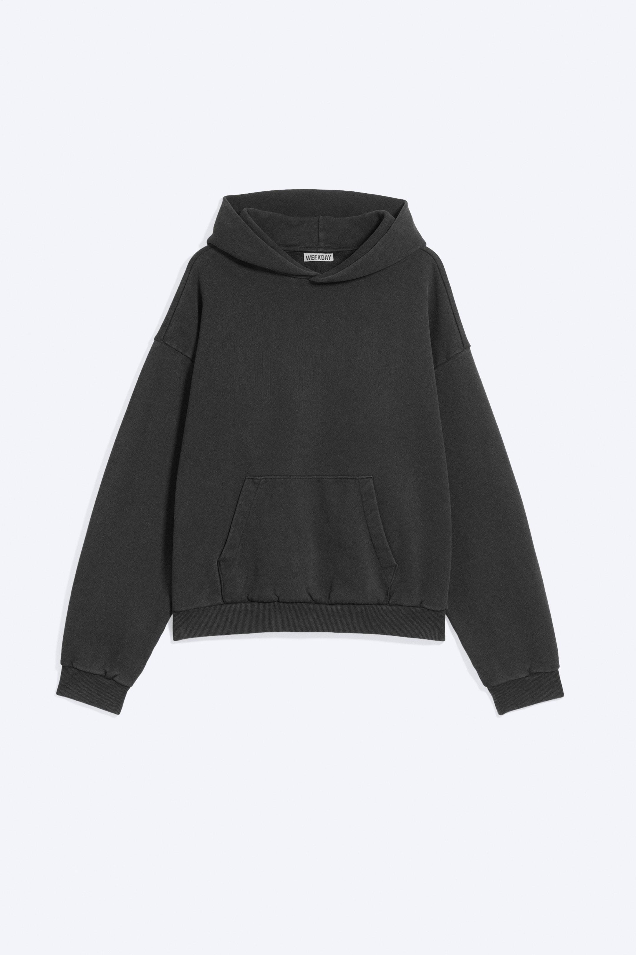 View larger image: A dark grey, loose-fit hoodie is shown from the front, featuring a structured hood without drawstrings and with a rounded silhouette, dropped shoulders, a classic kangaroo pocket, and ribbed elasticated cuffs and hem.