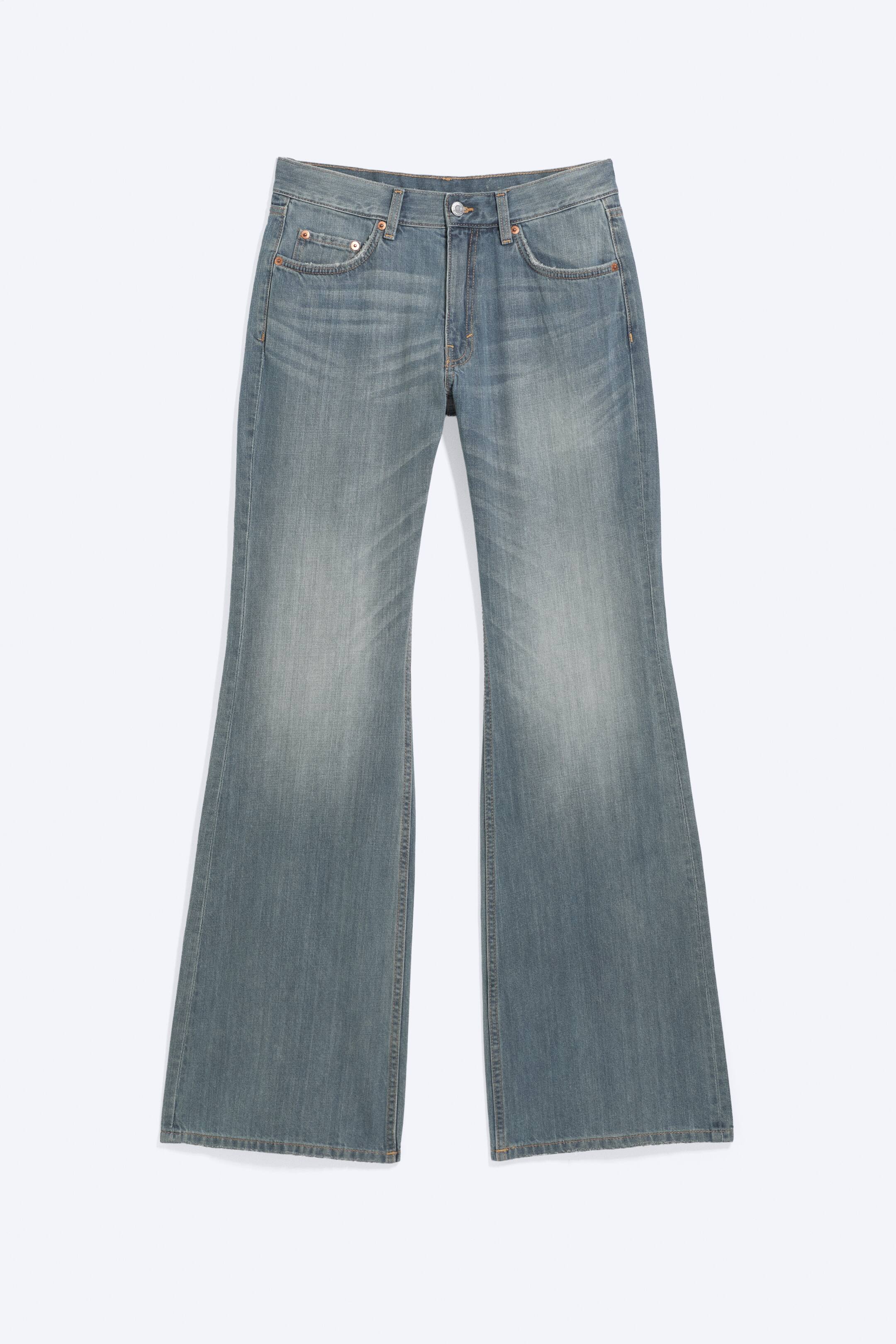 Agrandir l'image: Jean évasé bleu clair avec un délavage en denim décoloré, une fermeture à bouton et zip, et un style classique à cinq poches avec des rivets métalliques. Les jambes s'élargissent considérablement à partir du genou.