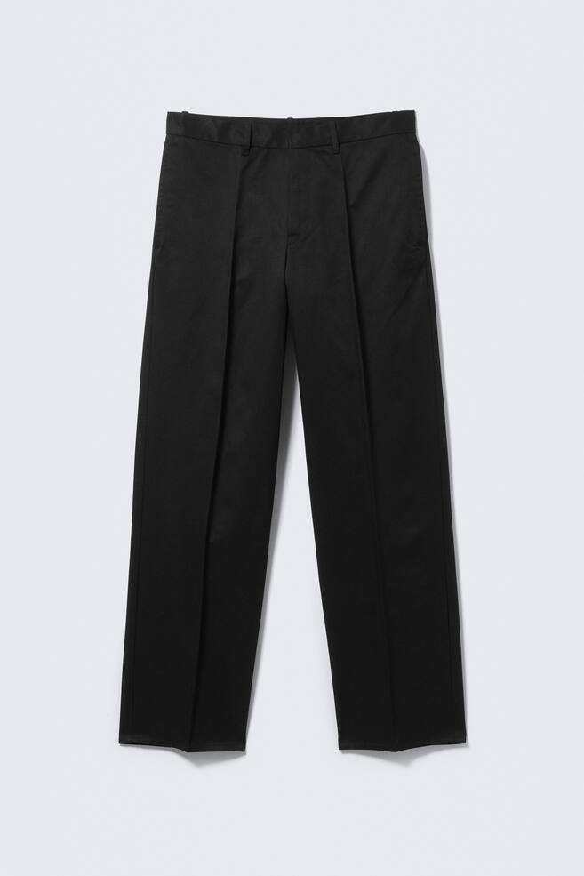 Black trousers are shown from the FRONT, featuring a waistband with belt loops, double pleats on each front leg, and side pockets. A distinct centre crease runs down the front of each leg. - 1
