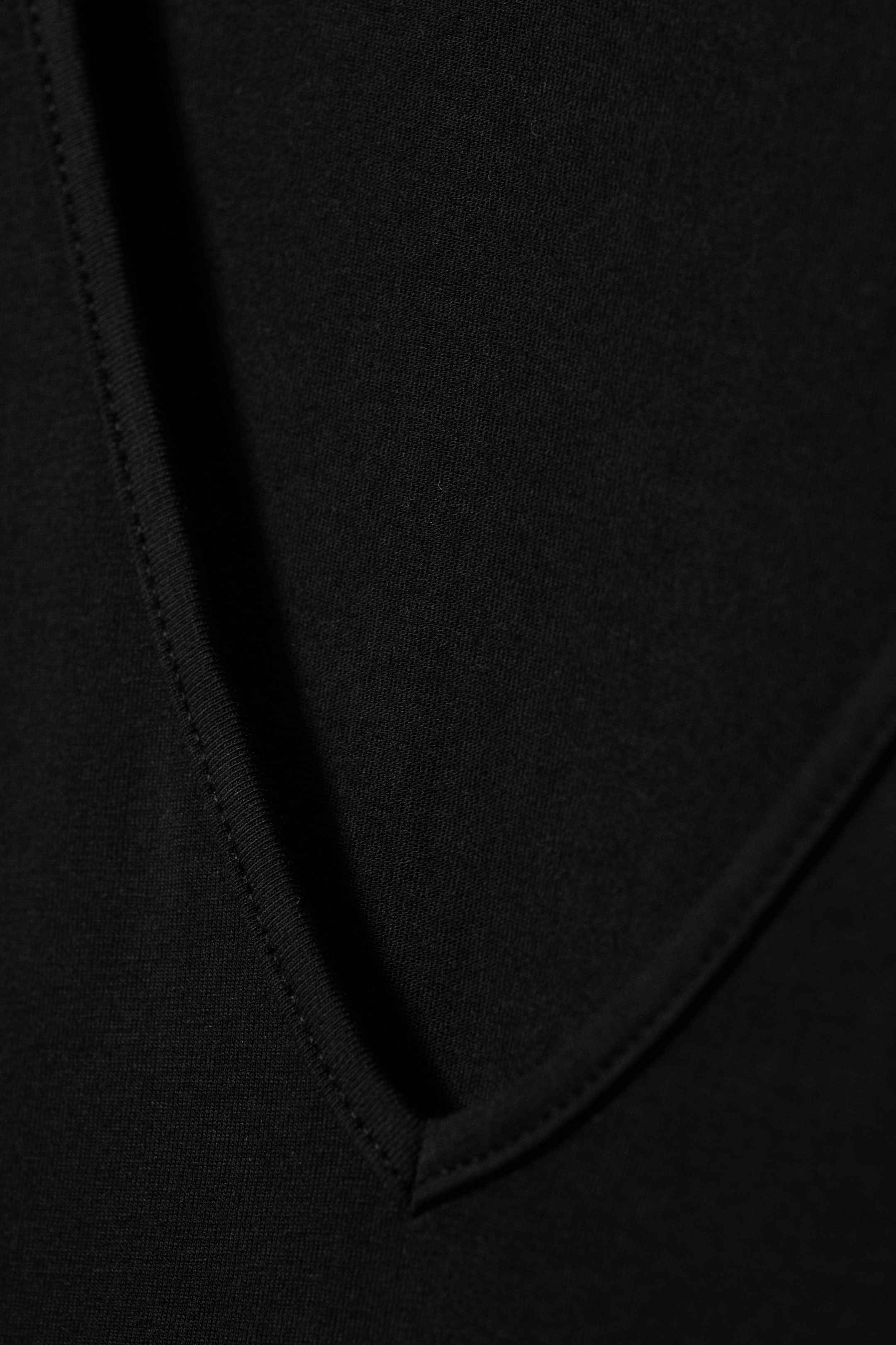 Größeres Bild ansehen: Der schwarze Stoff weist ein V-förmiges Design auf, mit sauberer Naht entlang der sich treffenden Kanten.