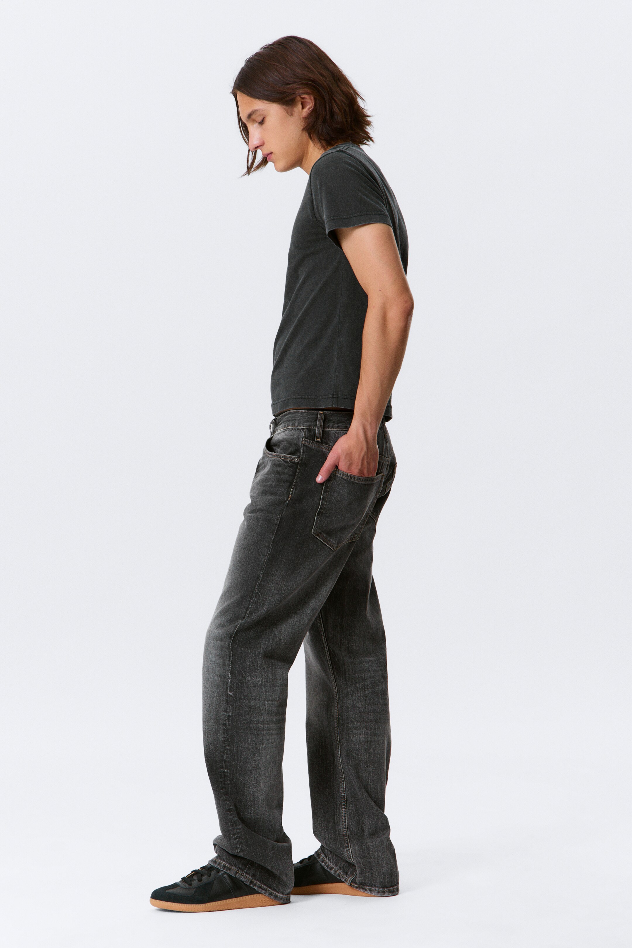 Größeres Bild ansehen: Ein dunkelgraues, kurzärmeliges T-Shirt und ausgewaschene schwarze Jeans mit entspannter Passform werden aus einem seitlichen Winkel präsentiert. Das T-Shirt verfügt über einen Rundhalsausschnitt und eine verblasste Waschung, während die Jeans eine gerade Passform mit sichtbaren Vorder- und Gesäßtaschen und einer abgenutzten Waschung aufweisen.