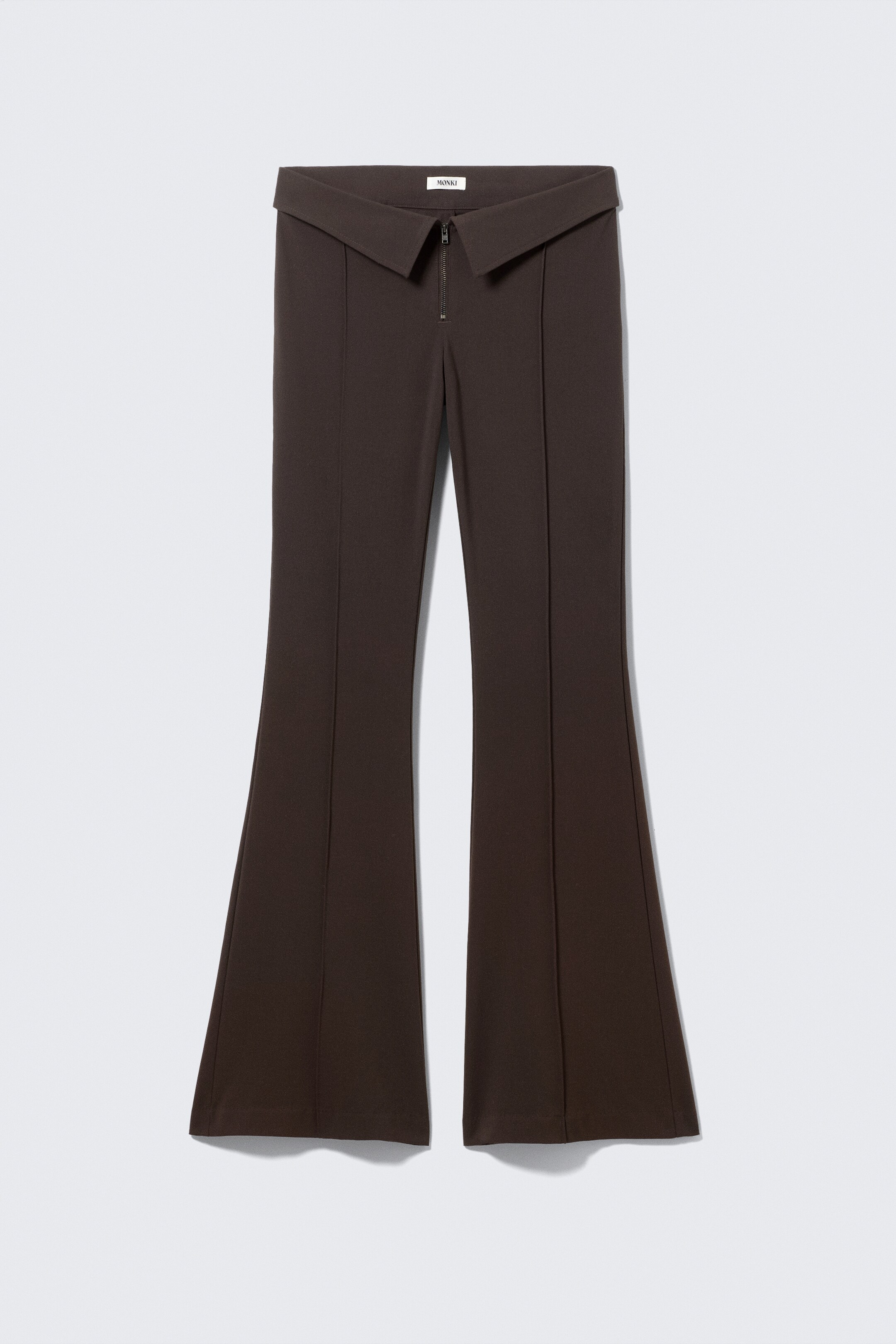 Agrandir l'image: Vue de FACE : Un pantalon évasé marron foncé présente une large ceinture rabattue avec une fermeture éclair visible. Des coutures verticales descendent au centre de chaque jambe, et les jambes s'évasent à partir du genou.